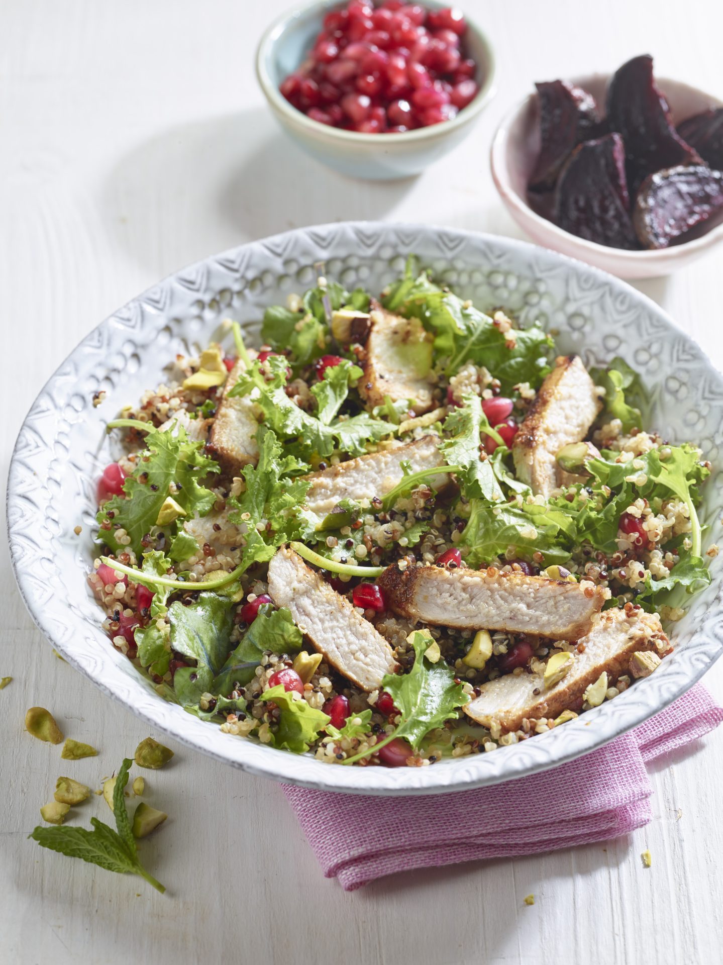 Sliced pork medallions on bed of salad leaves in a white bowl