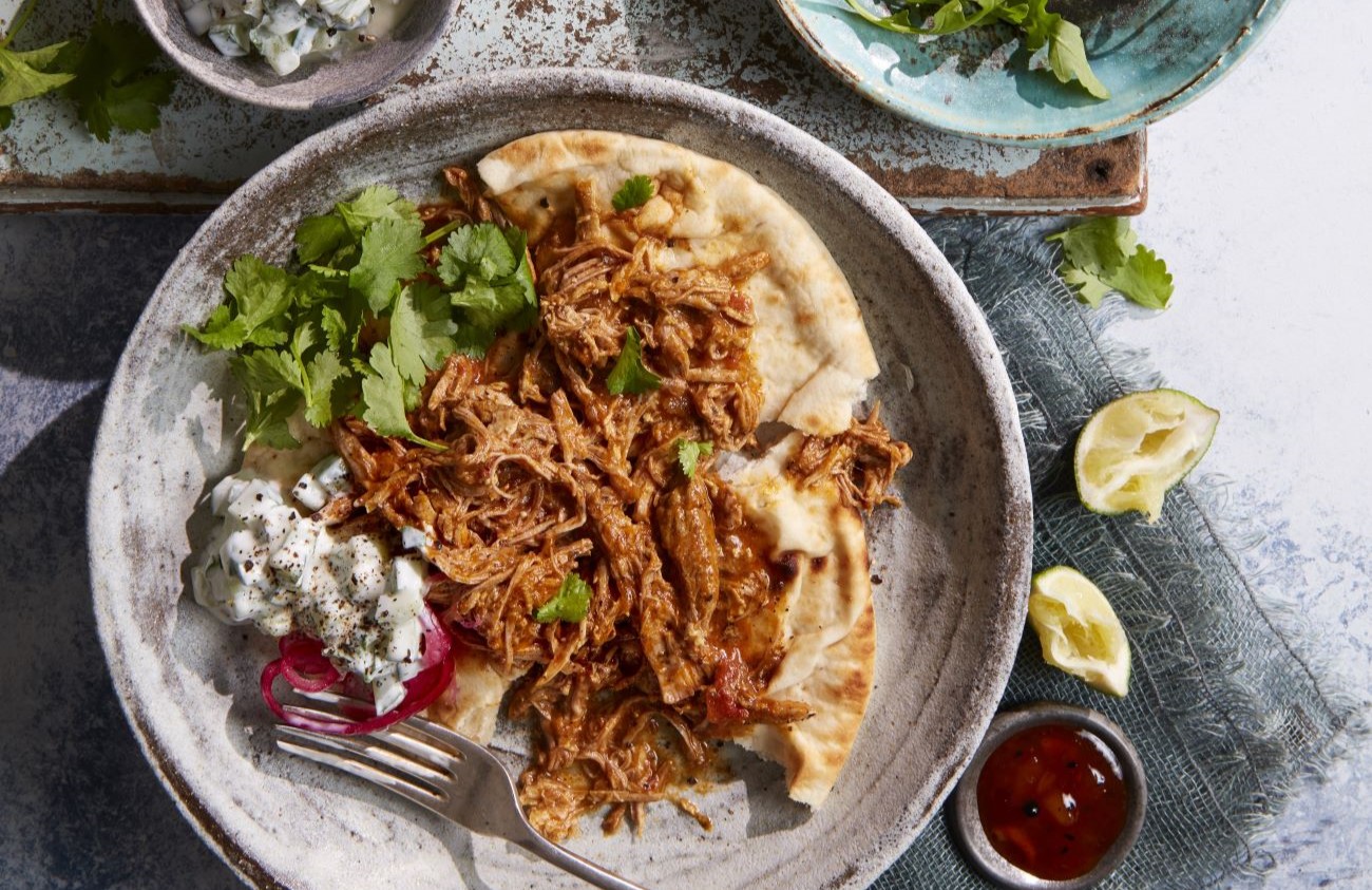 Plate of curried pulled pork on grey plates with sides.