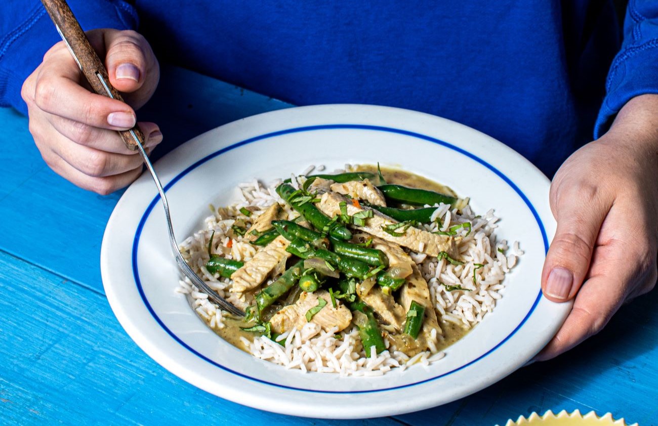 thai green pork curry with green beans served with rice on white plate