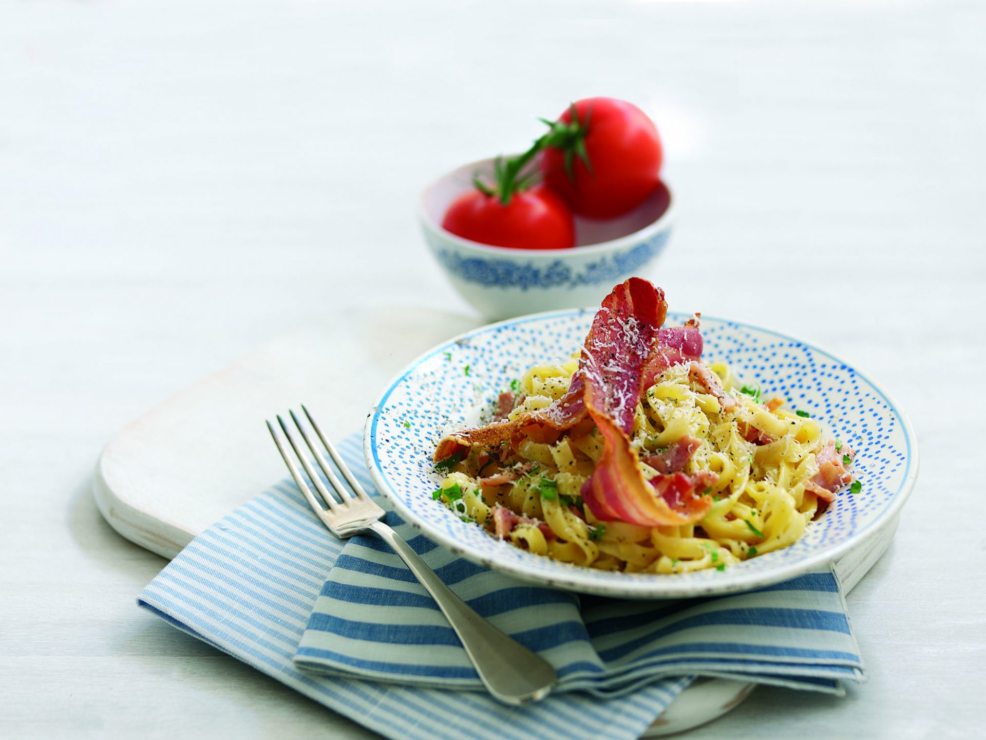 Bowl of tagliatelle carbonara with crispy bacon on top