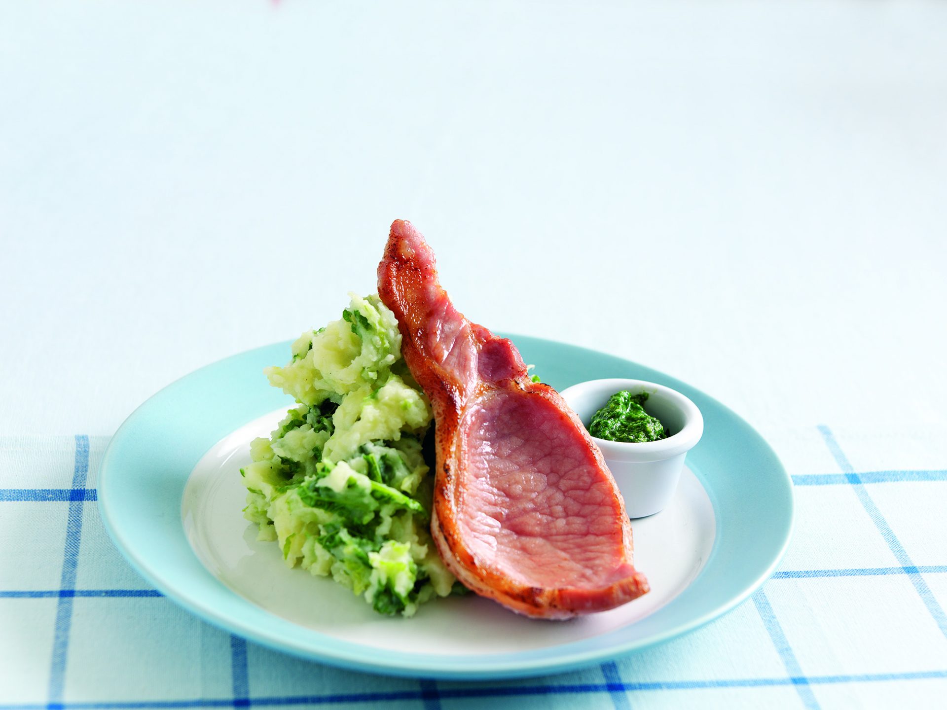 Rasher of bacon on top of colcannon on a blue plate