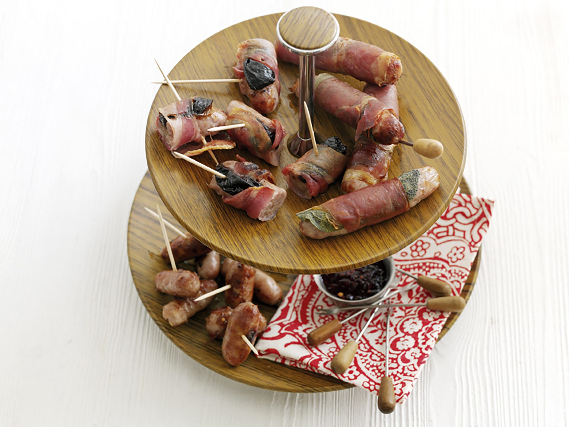 Sausages wrapped in sage and ham displayed on a two tier cake stand