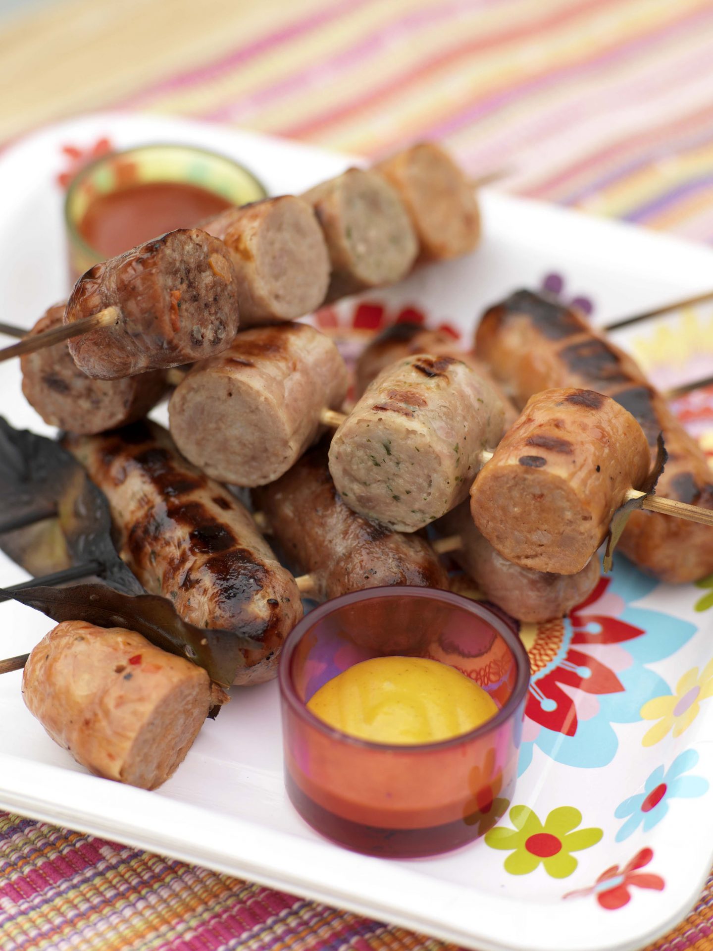 Cooked sausage skewers with small orange dip on side