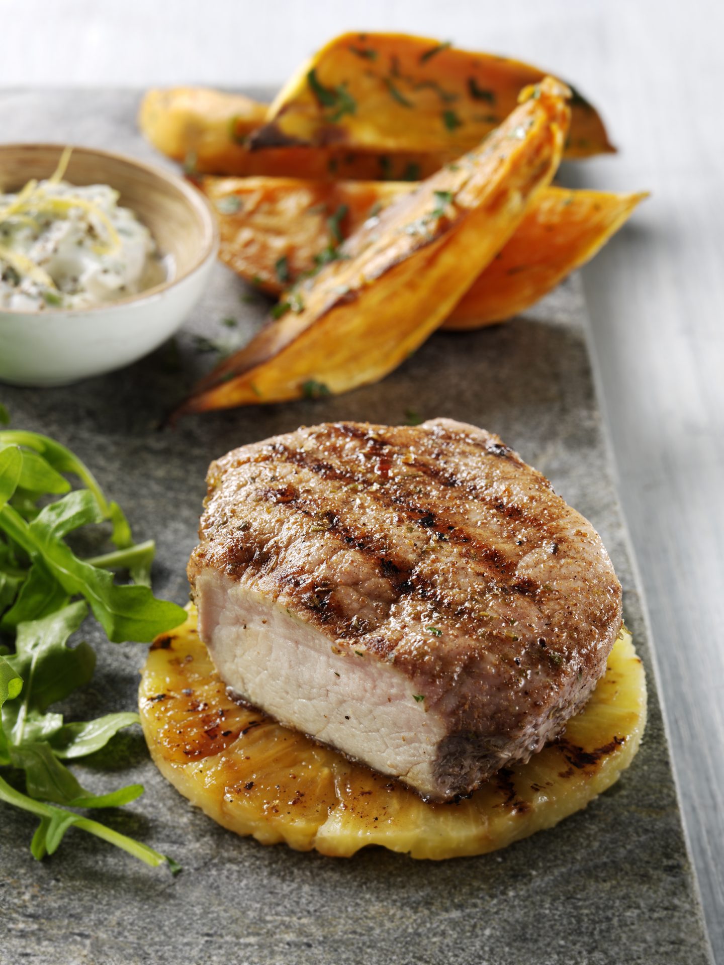 Grilled pork medallion with potato wedges in background