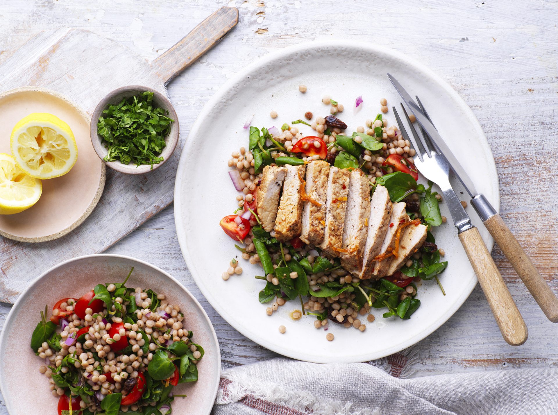 Sliced cinnamon pork on a bed of wholegrain couscous and green leaves