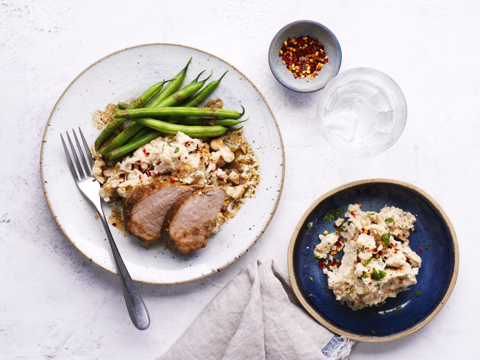 Two pork fillet slices with a cannalleni mash, on a white plate with fork