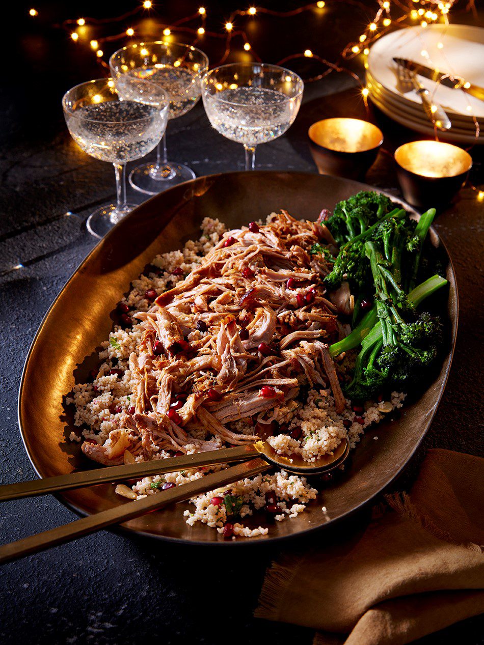 Large platter full of festive orange and cranberry pulled pork, with serving spoon