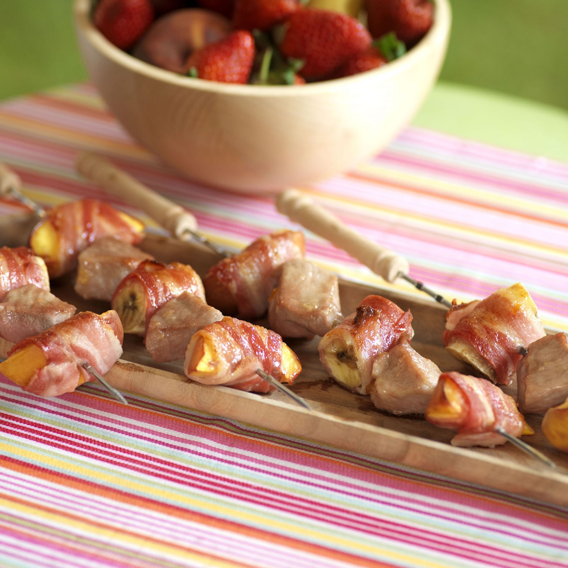 Steaky bacon wrapped fruit kebabs on a serving platter