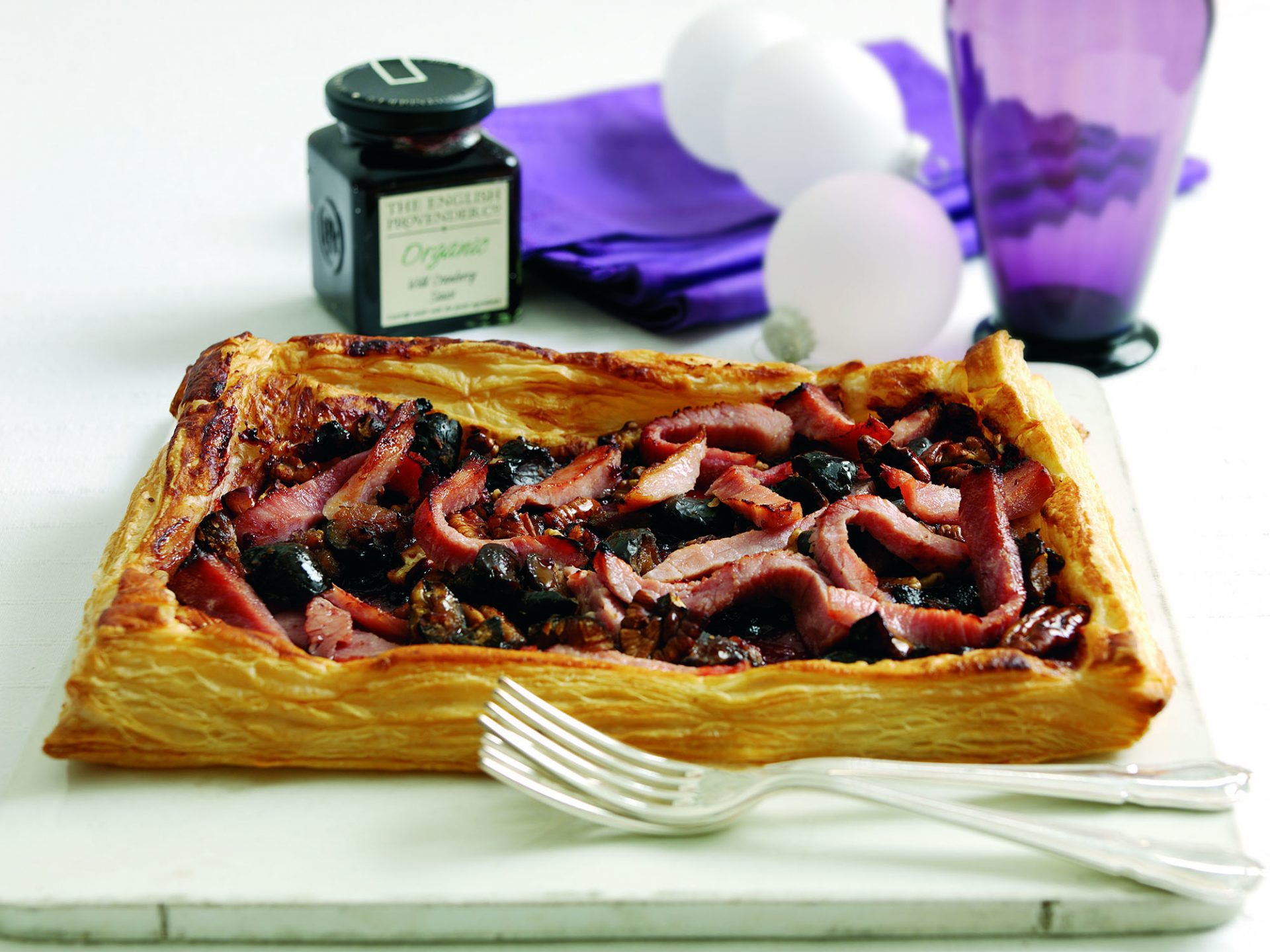 Gammon cranberry and chestnut tart on a pale board with forks on side.