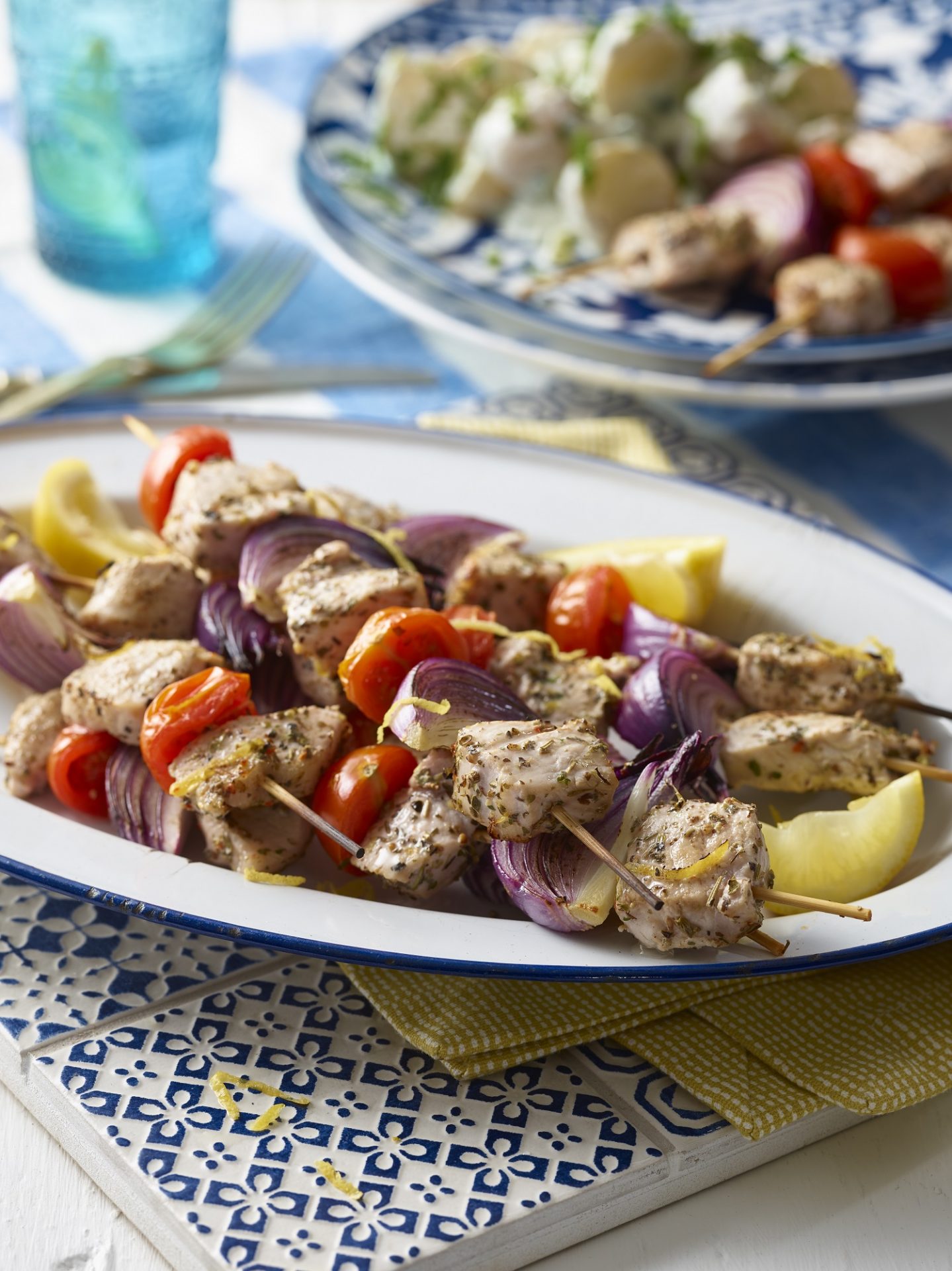 Pork and vegetable skewers on a large white serving dish