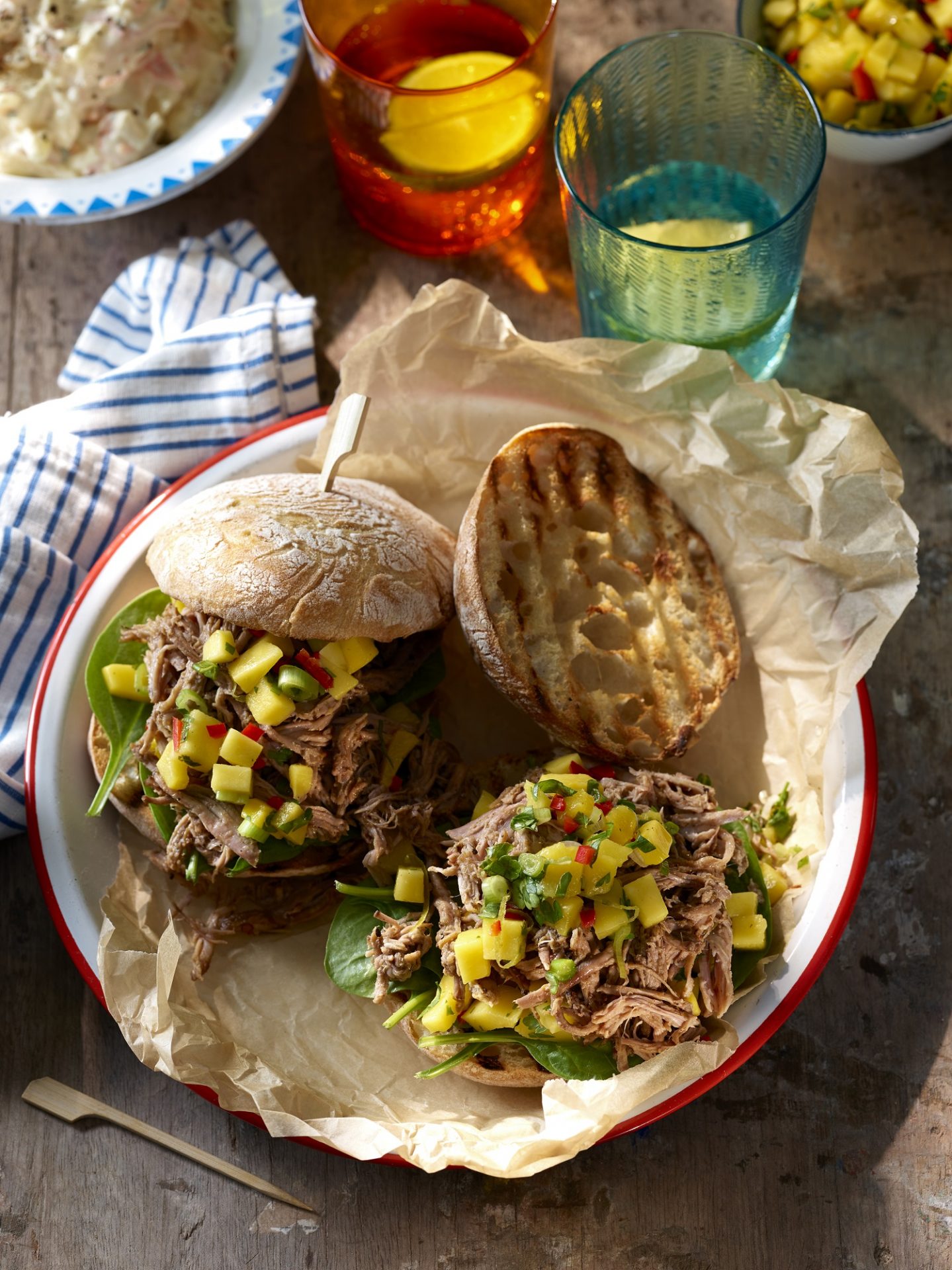 Two burger buns filled with pulled pork and topped with mango salsa