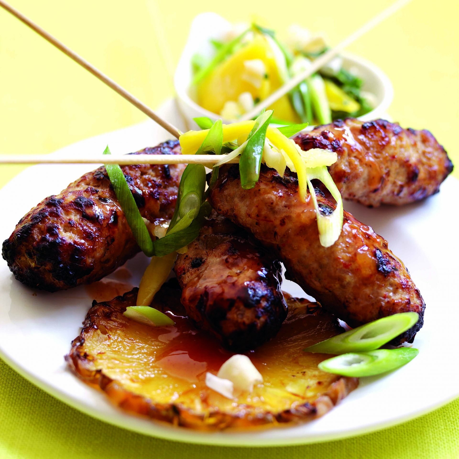 Pork skewers with a creole sauce served on a white plate