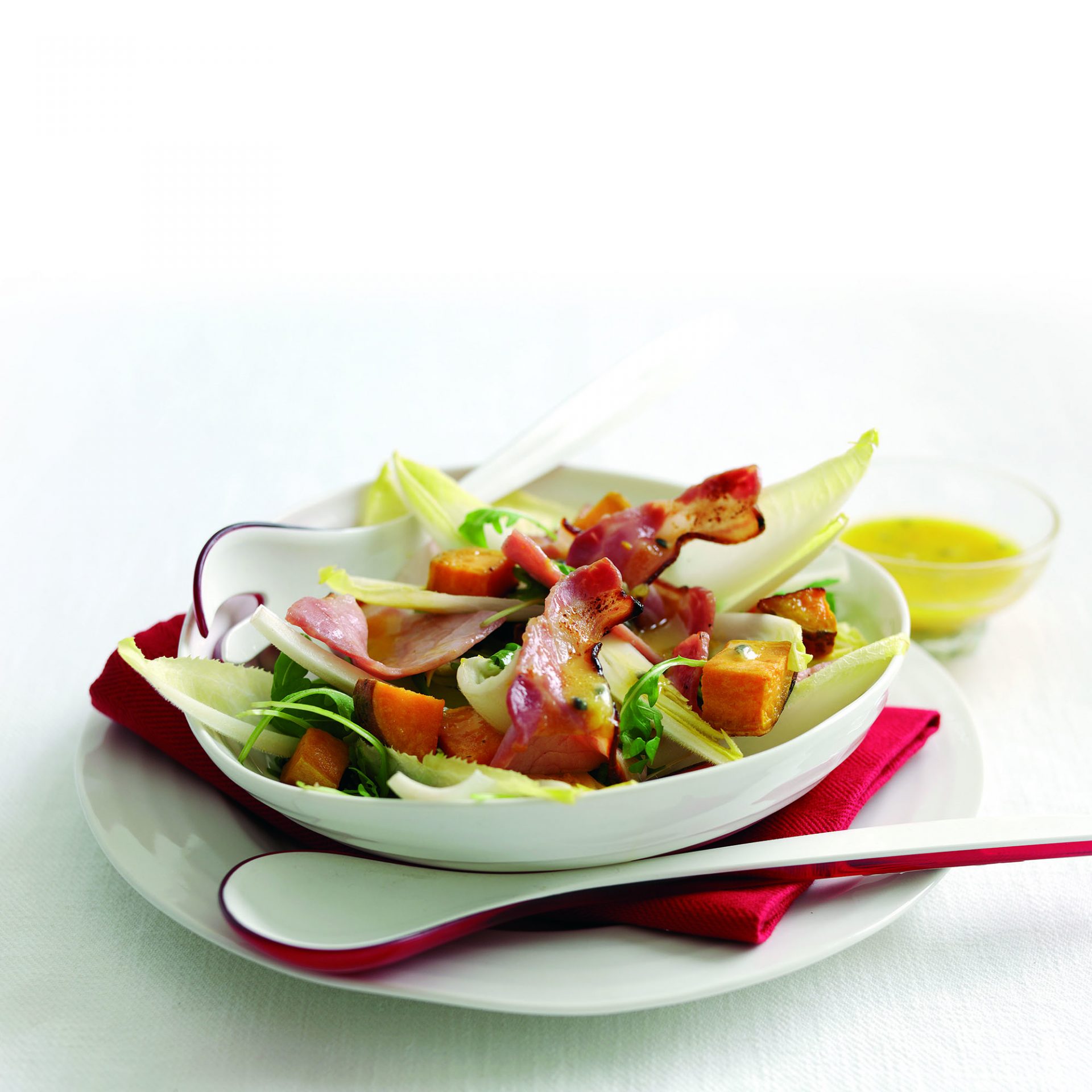 Maple and chicory bacon salad served in a white bowl.