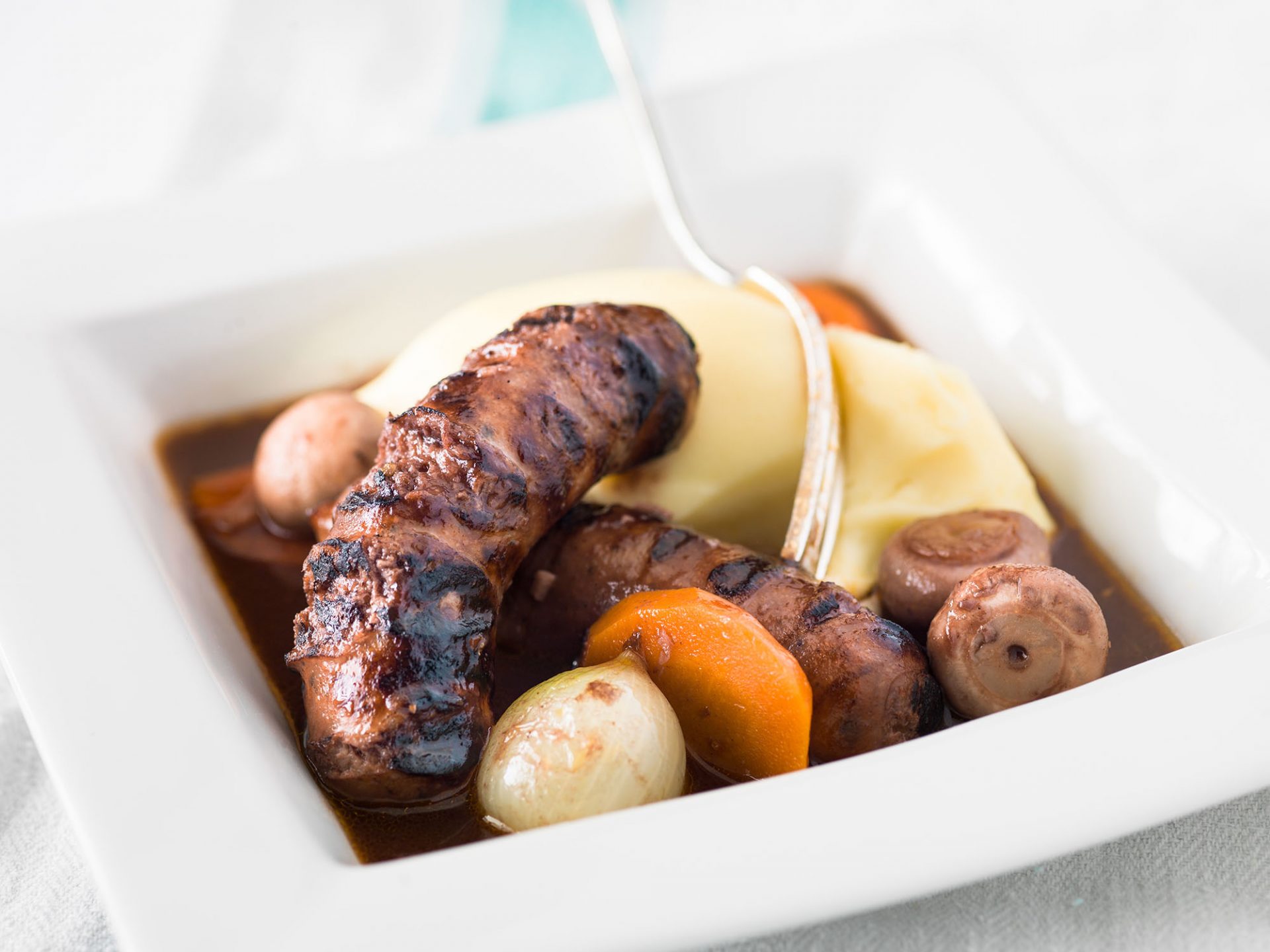 Sausage bourguignone served in a white bowl.