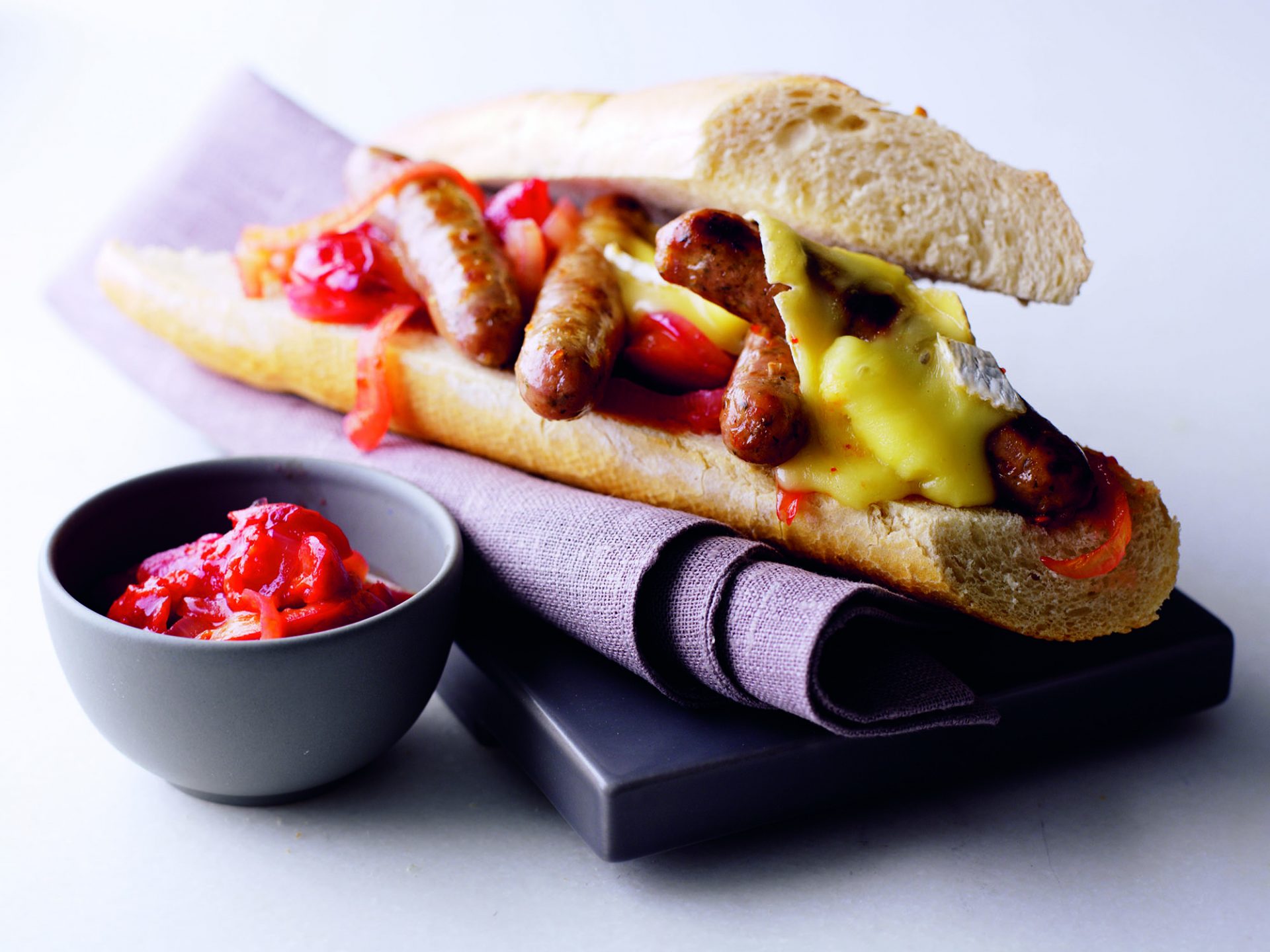 Chipolata sausages with brie in a baguette roll