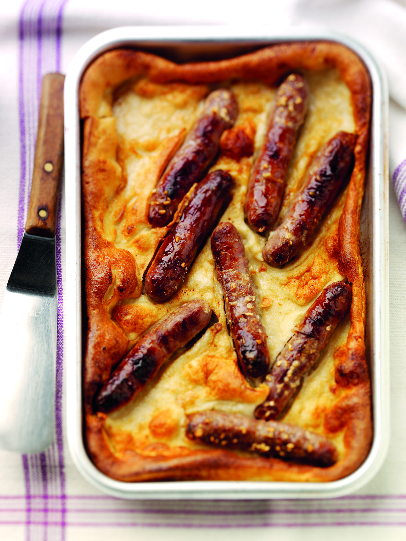 Eight pork sausages in a toad in the hole, in a large white casserole dish