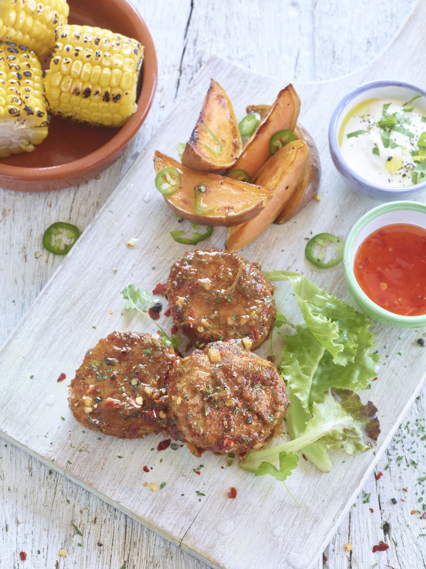 Three pork fillet medallions with wedges and dips served on a white board