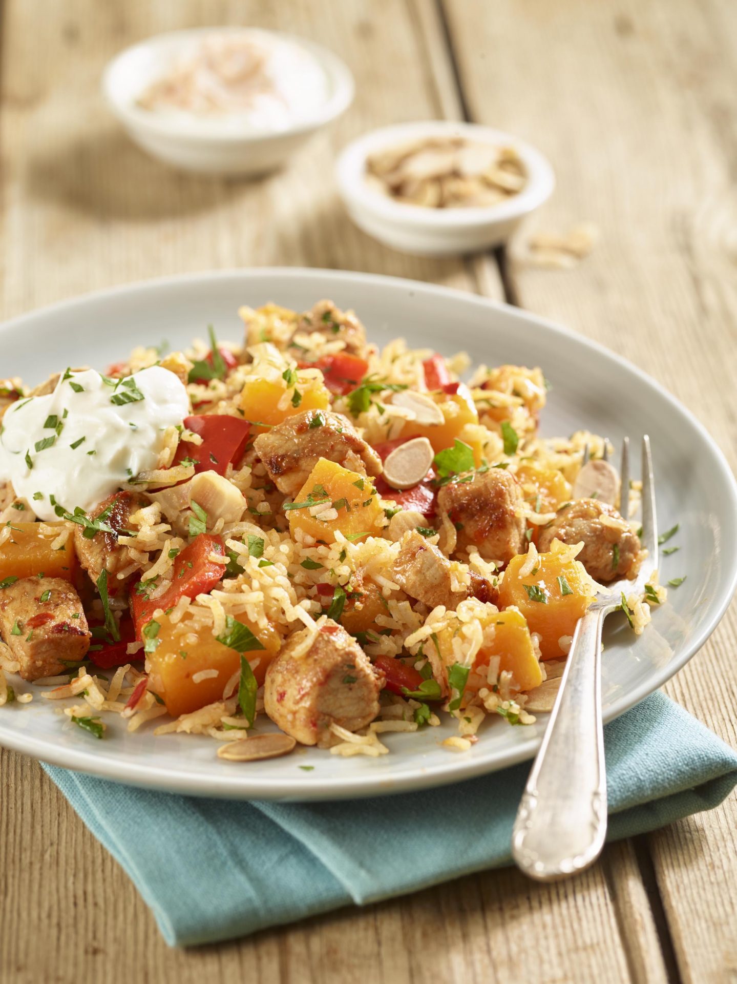 Pork and pumpkin pilaf served on a plate with fork, with spoonful of yoghurt on top