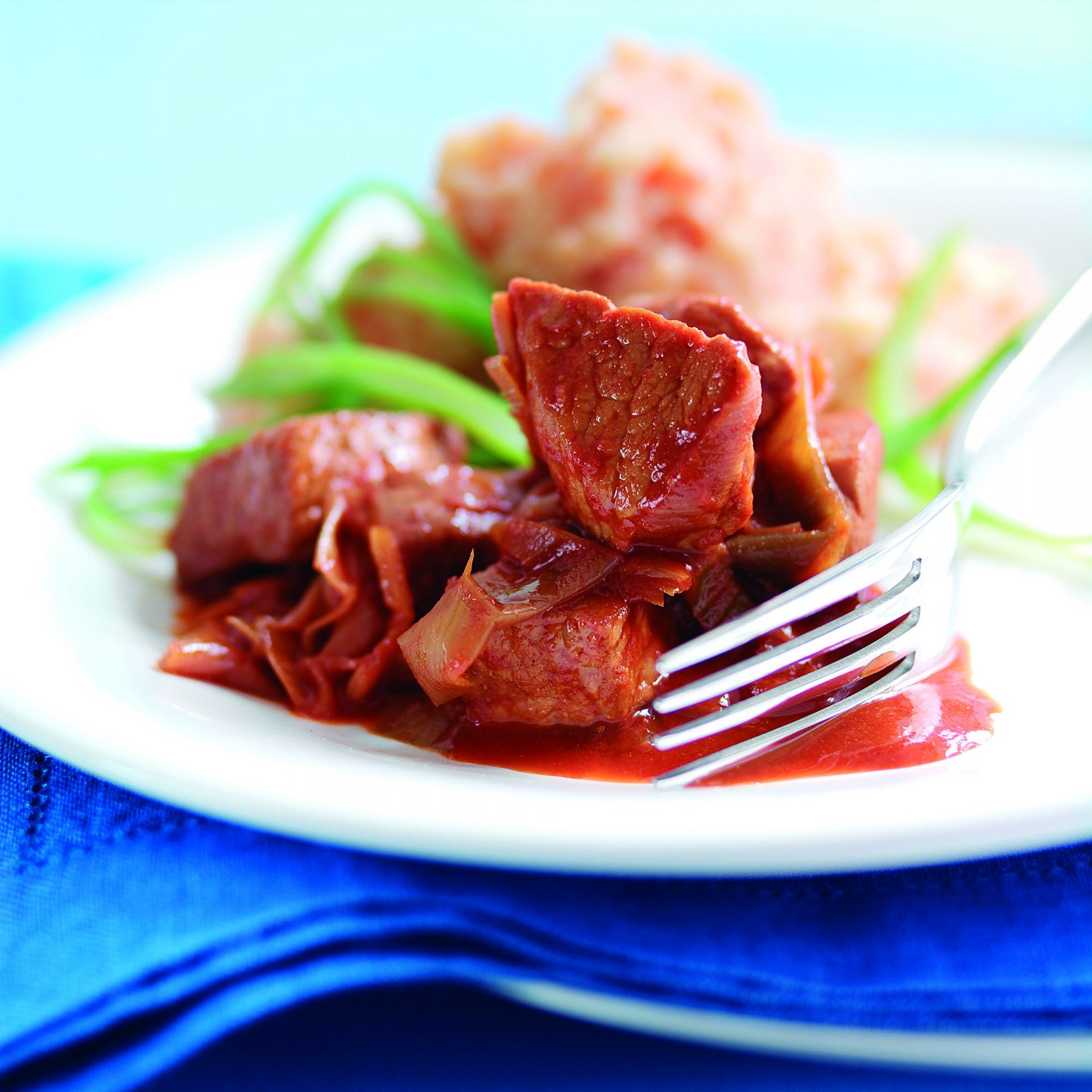 Pork chunk piquant casserole served on a white plate with fork scooping