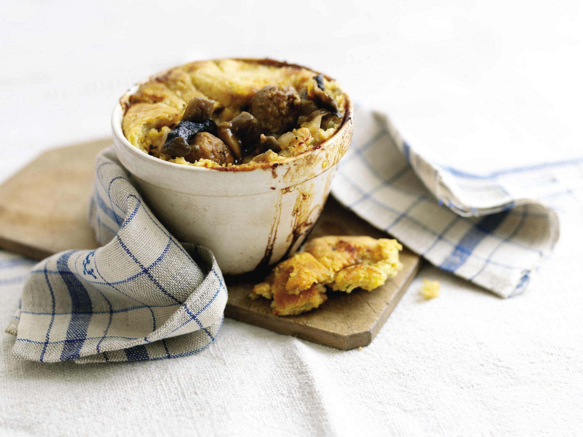 Pork and tomato sausage mini puddings served in a small white ramekin with tea towel.