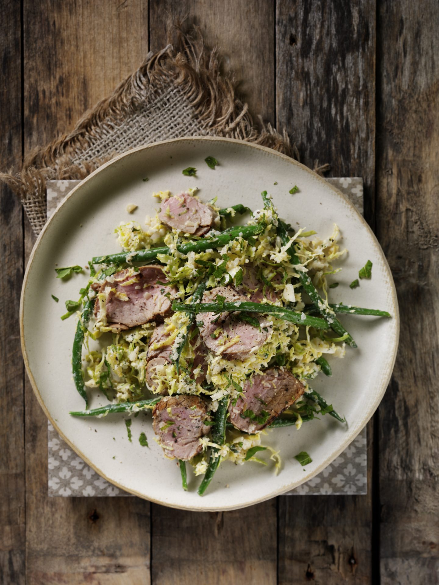 Slice pork fillet with a green vegetable salad served on a white plate