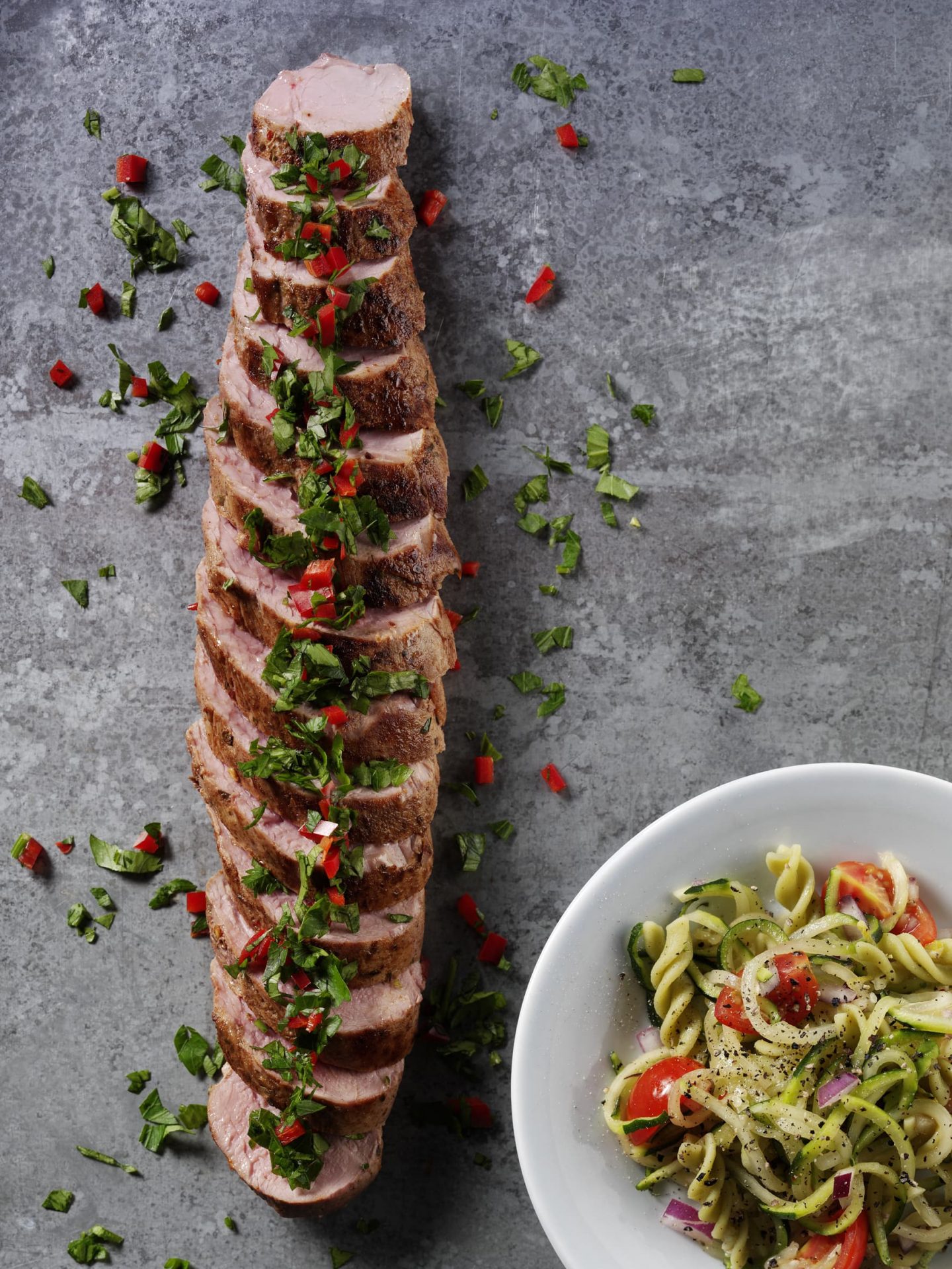 Sliced pork fillet on a grey board.