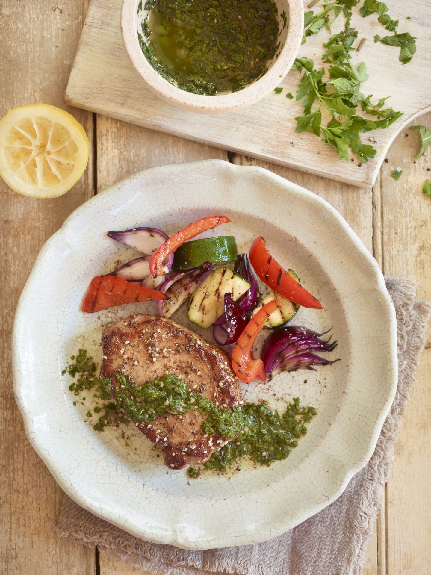 Pork loin steak with salsa verde served with vegetables on a white plate