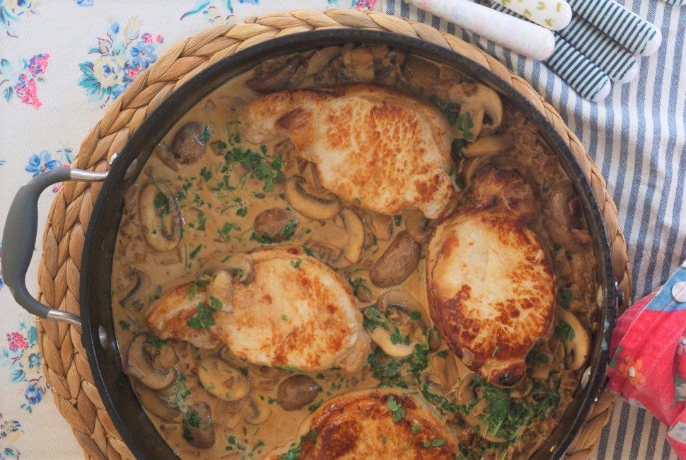 Four pork loins in a creamy mushroom sauce, in a large black pan