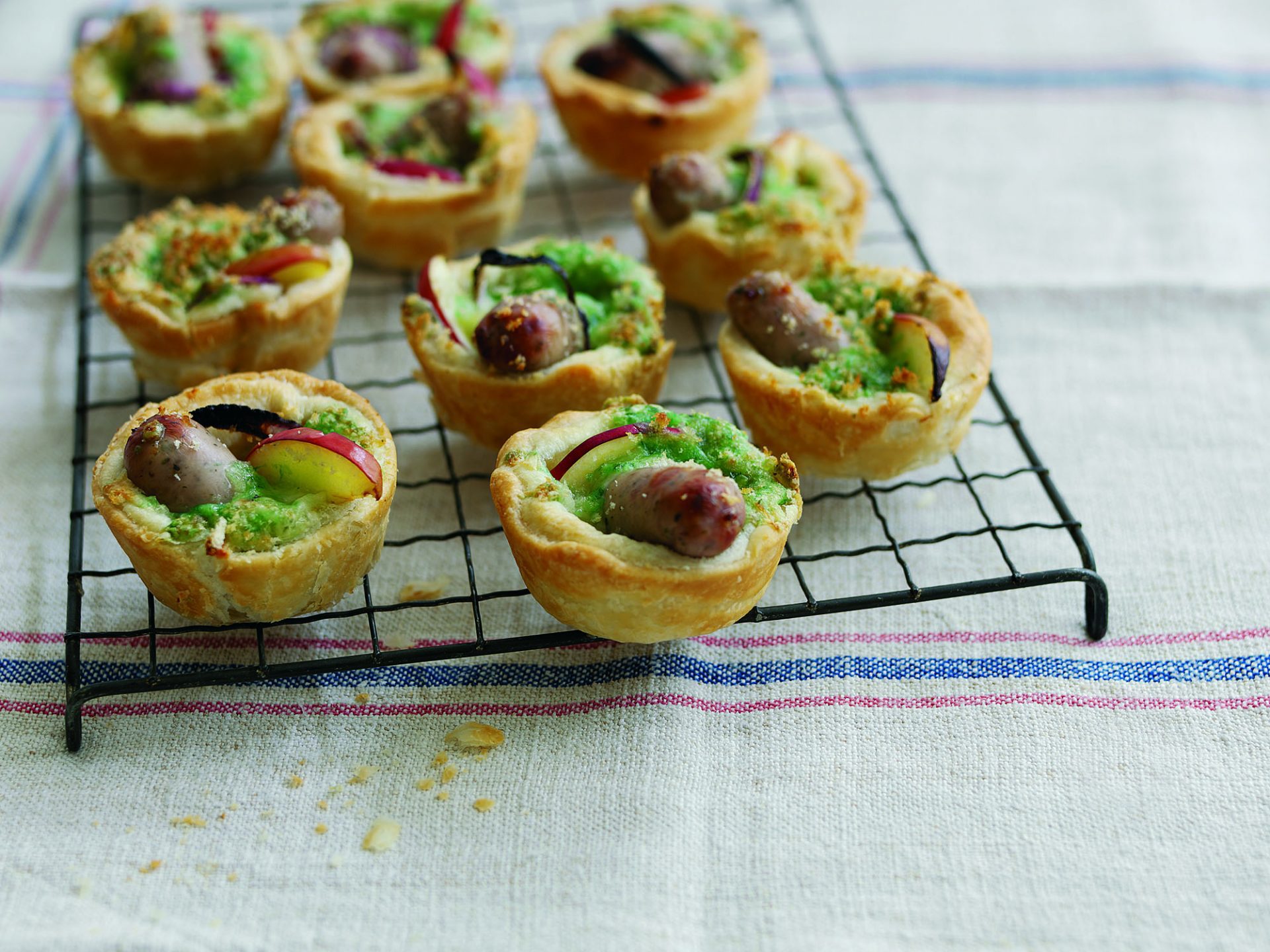 Multiple mini pork sausage bakewell tarts on a baking rack