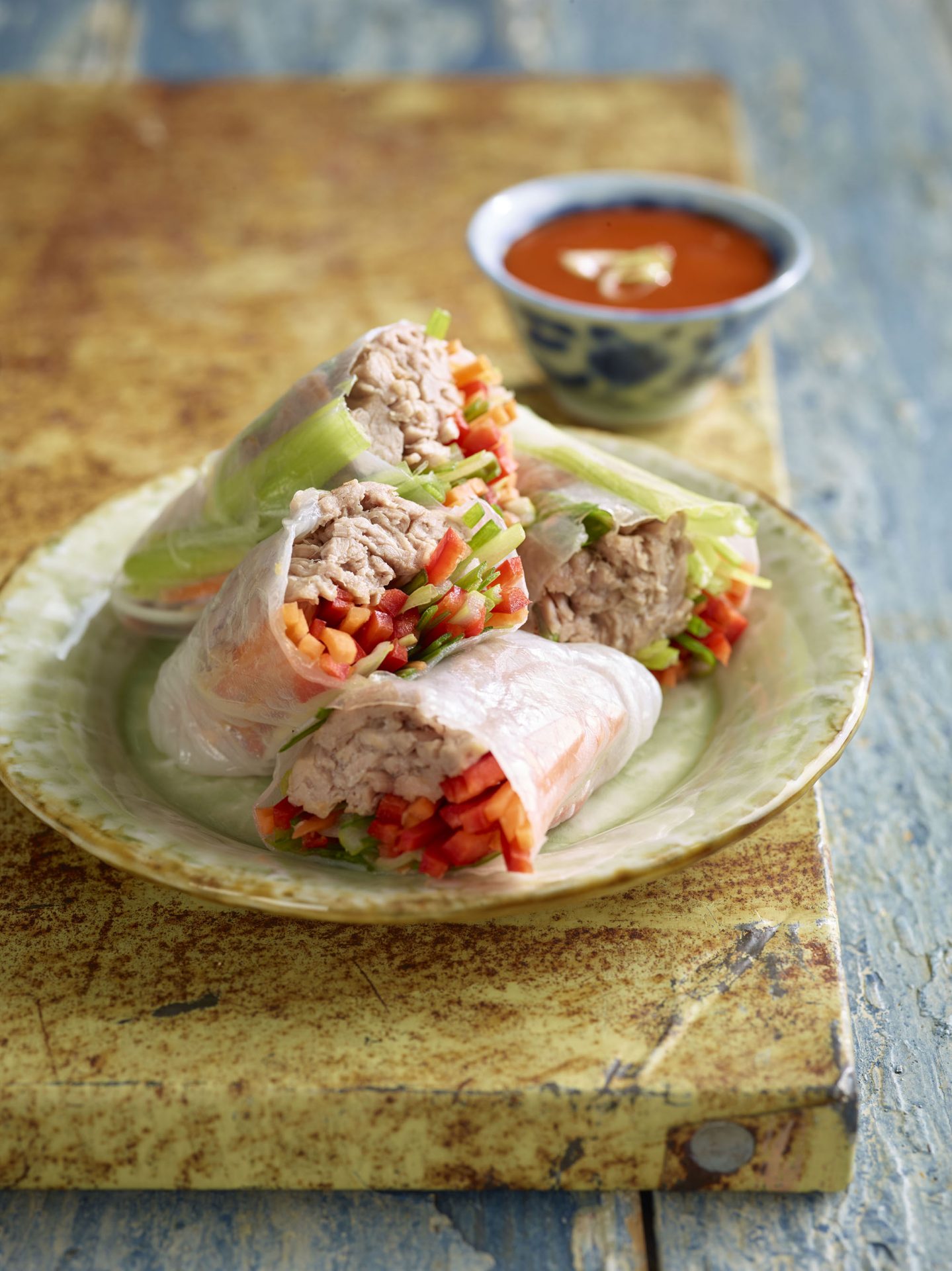 Four vietnamese pulled pork and vegetable rolls served on a pale green plate