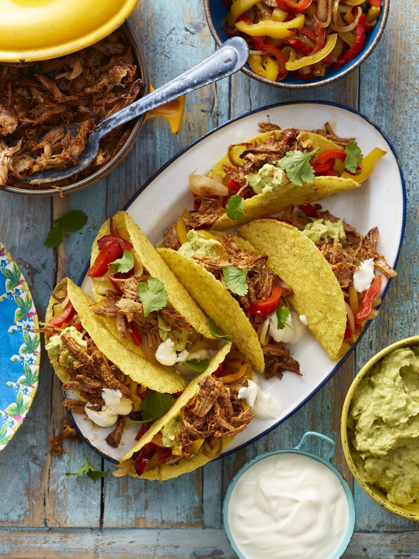 Large serving plate with multiple taco shells filled with pulled pork