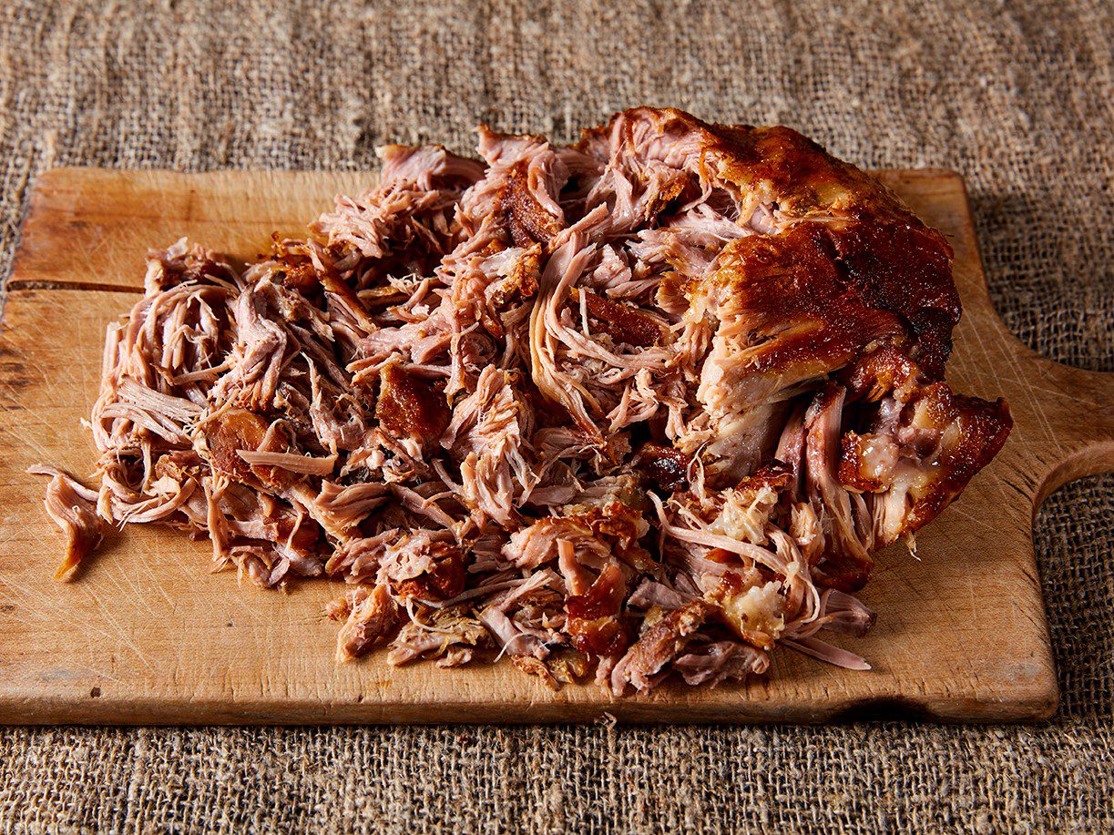 Pulled pork, shredded, on a wooden chopping board