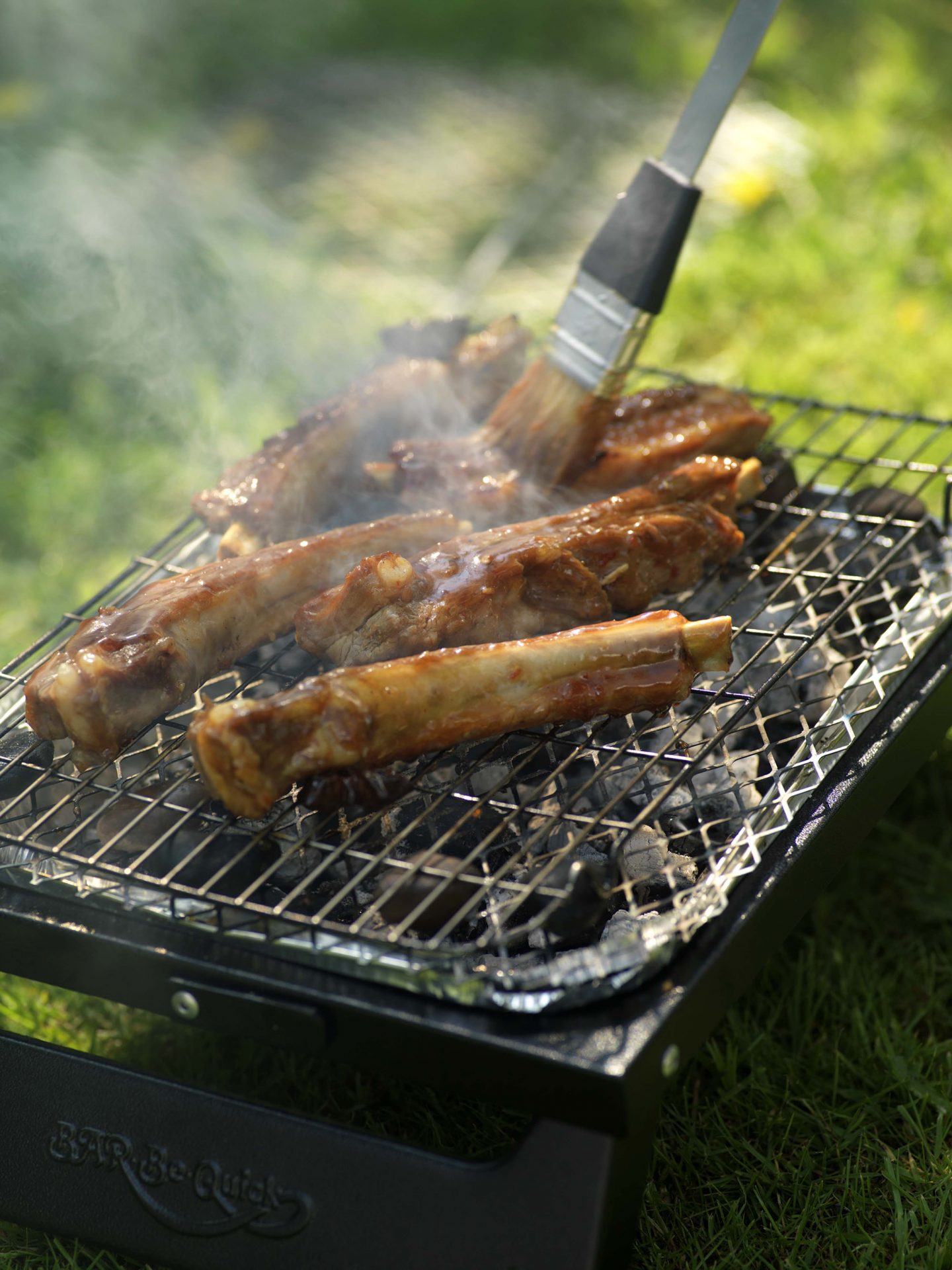 bbq ribs on the bbq being brushed with glaze