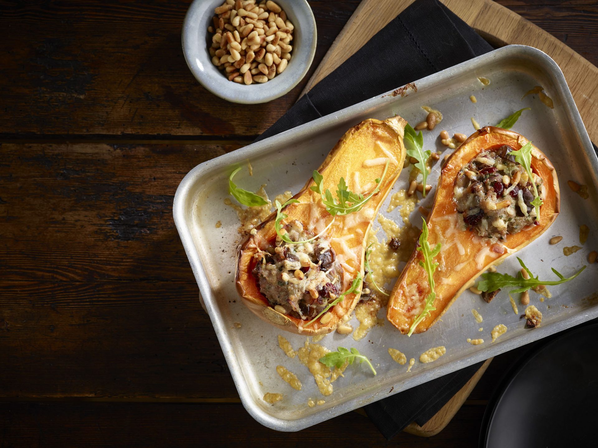 Sausage stuffing filled roasted butternut squash in a metal baking tray