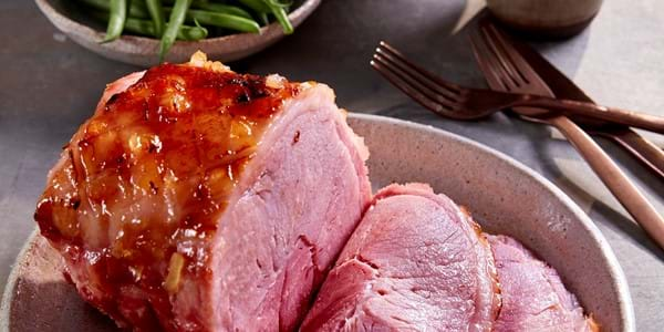 Roast gammon joint, some sliced, on a white plate