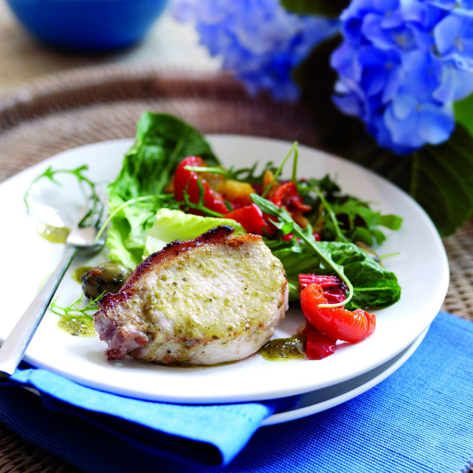 Single pork steak served with salad on a white plate with fork.