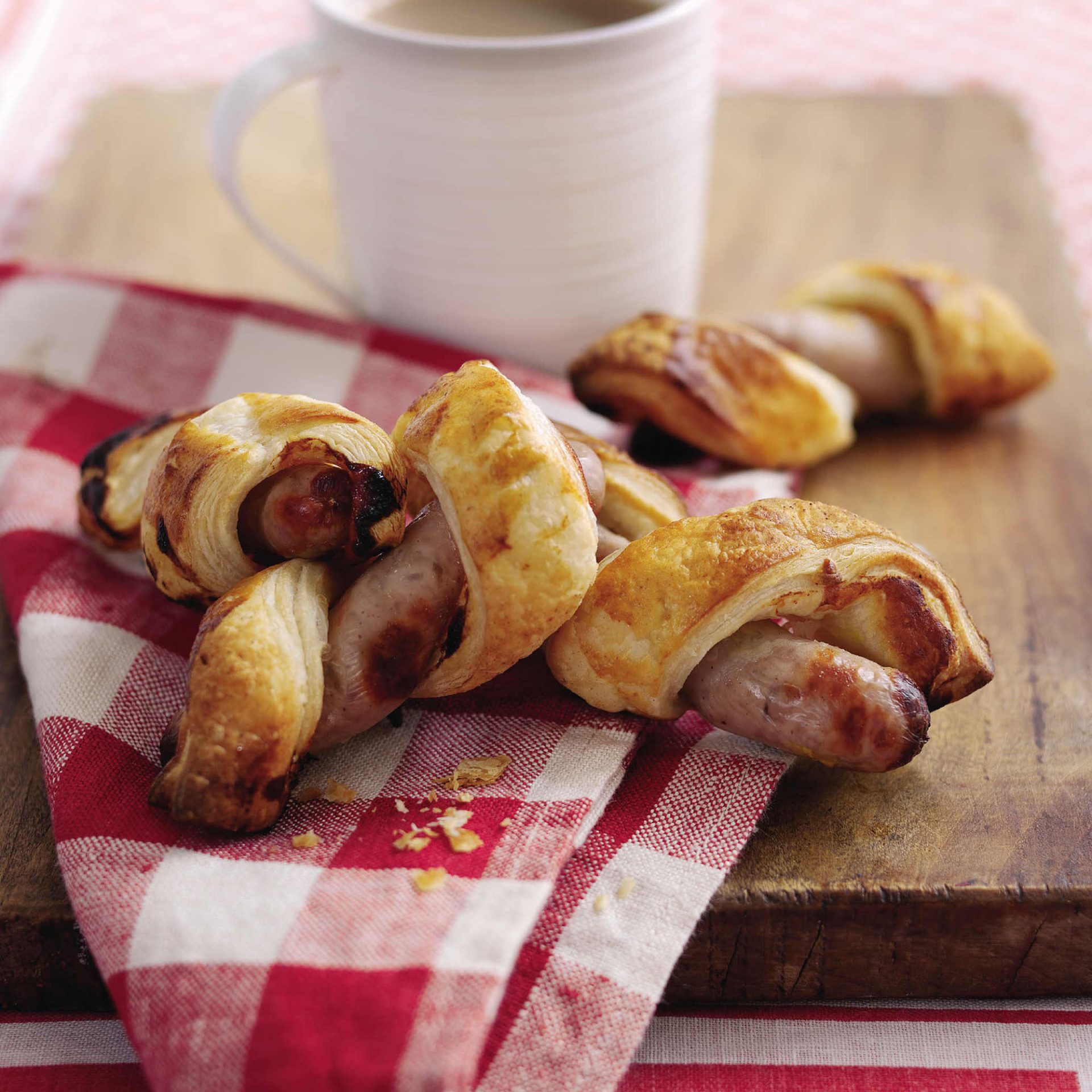 Four sausages wrapped in puff pastry, on a red napkin.