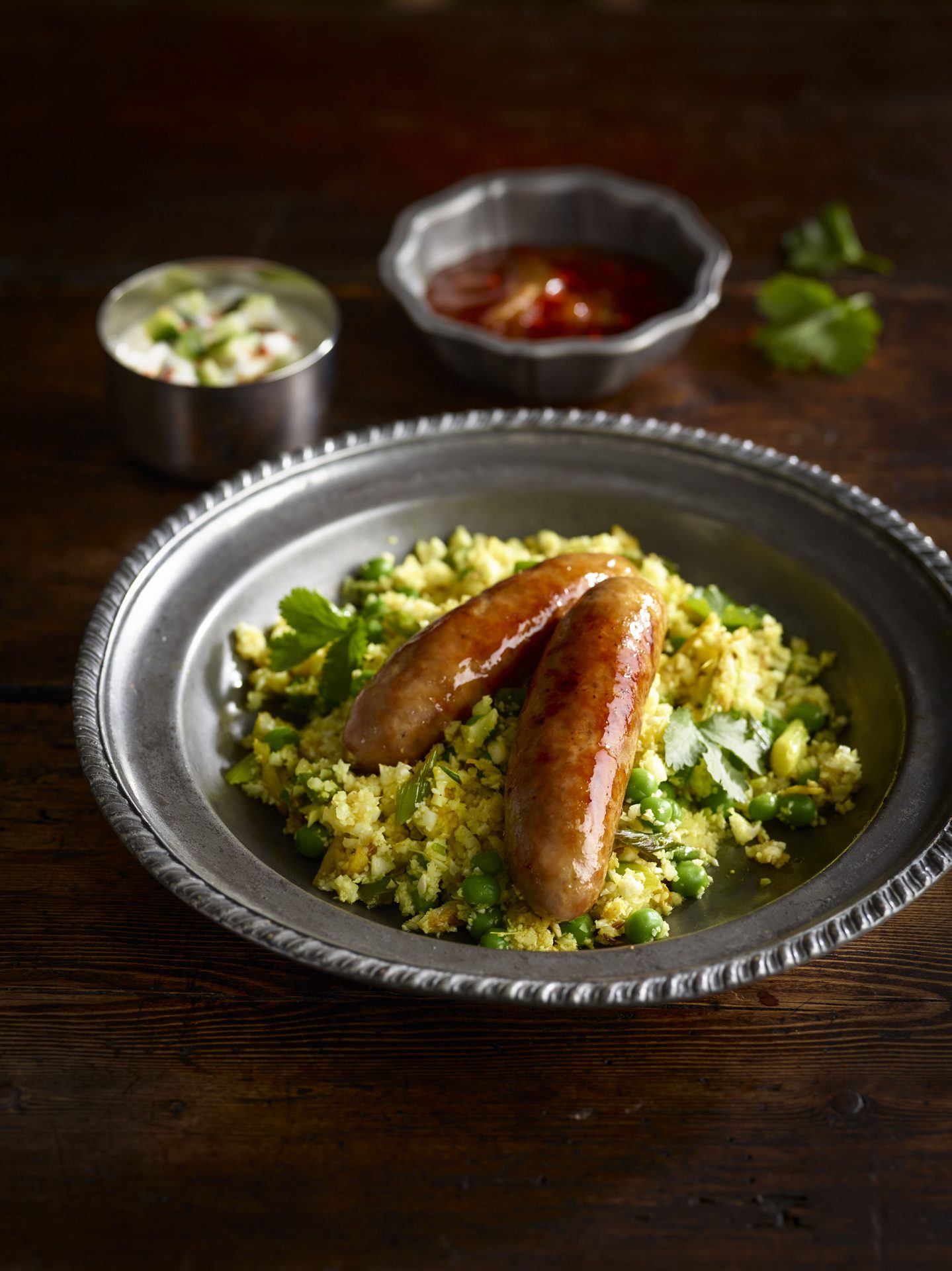 Two sausages on a bed of spicy cauliflower rice in a black bowl