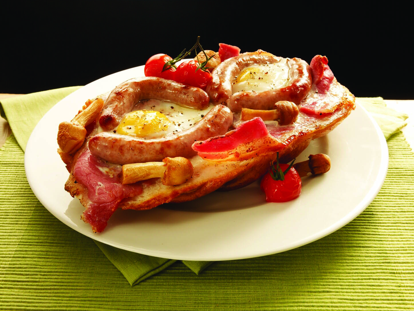 Sausage bacon egg tomato breakfast in the shape of a face on a white plate