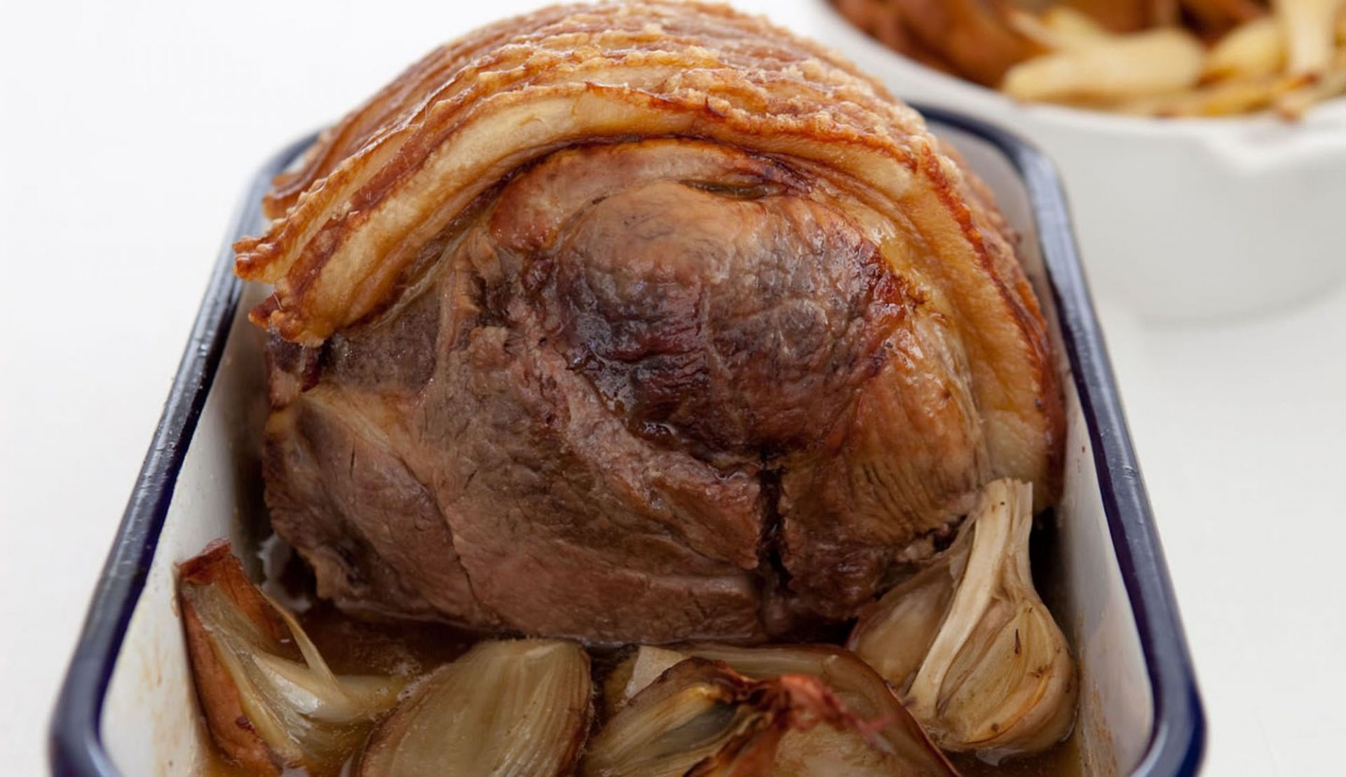 White baking tray with a rolled shoulder of pork