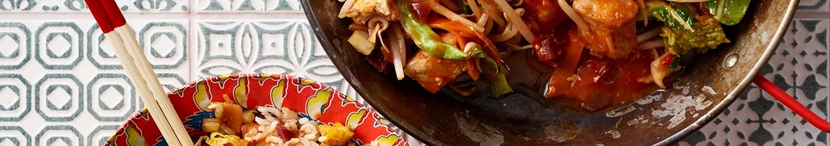 Two decorative bowls with chopsticks, filled with sweet and sour pork stir fry