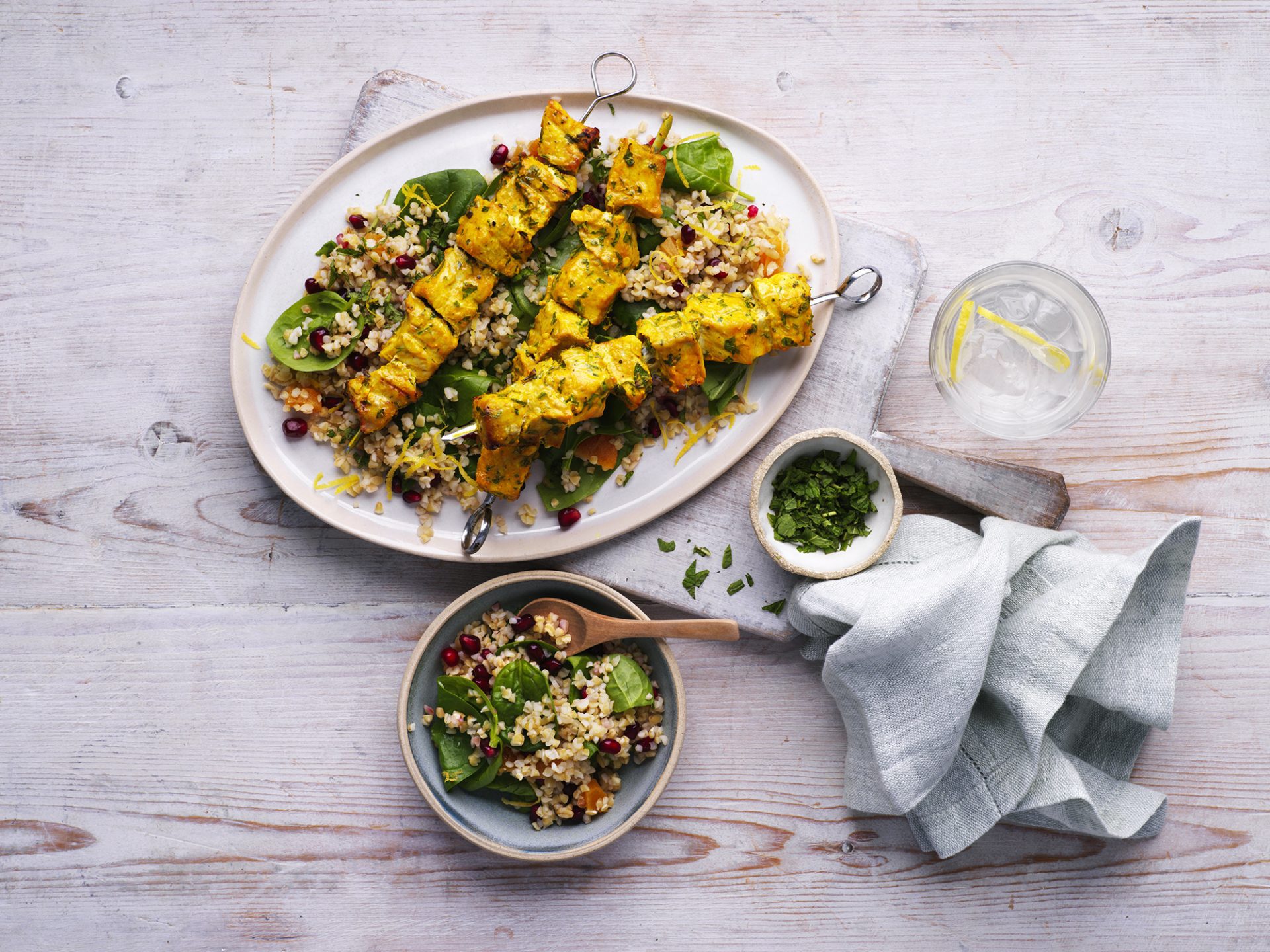 Two turmeric pork skewers with supergrain salad served on a white plate