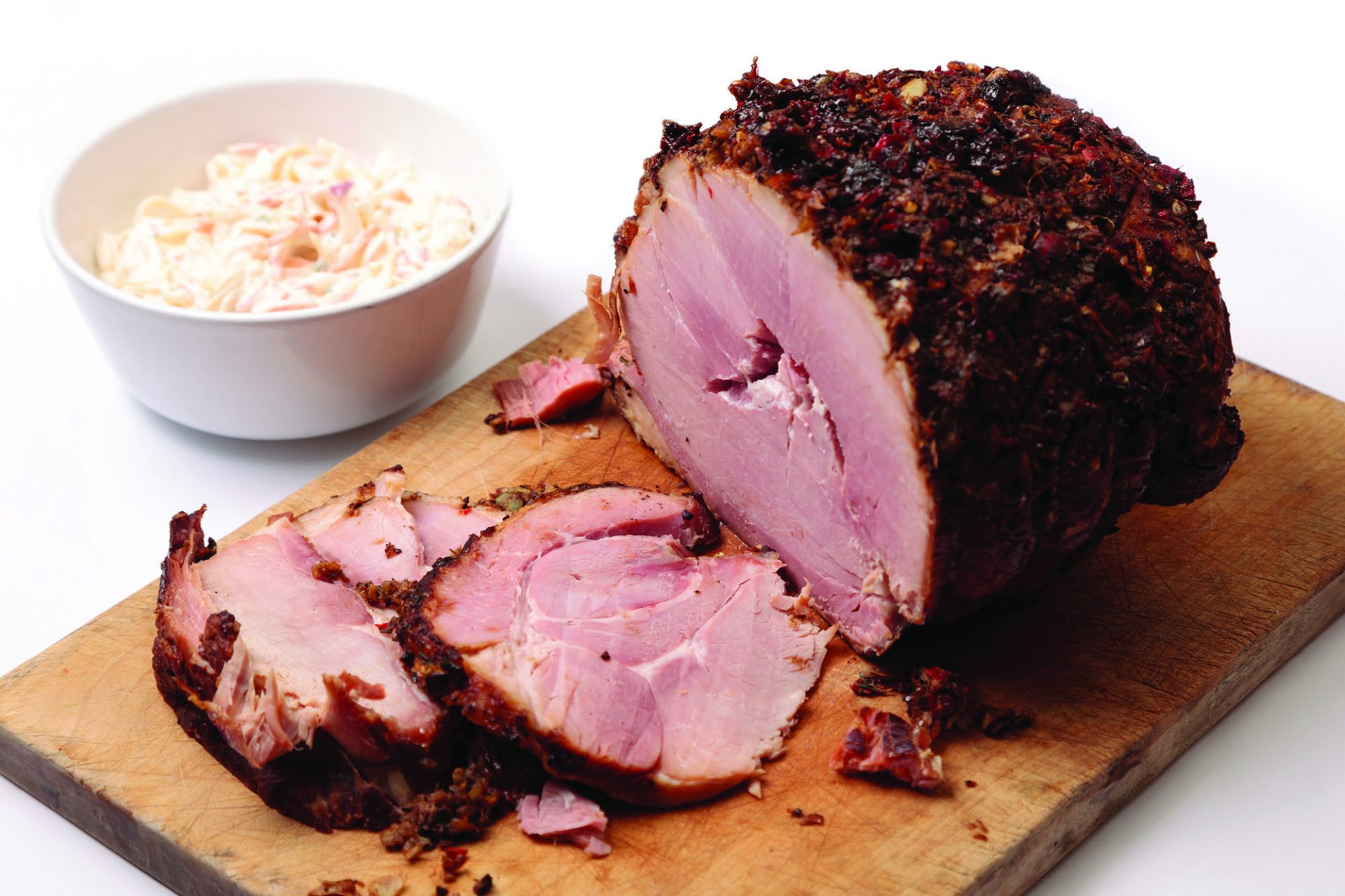 Gammon joint, some sliced, on a wooden chopping board