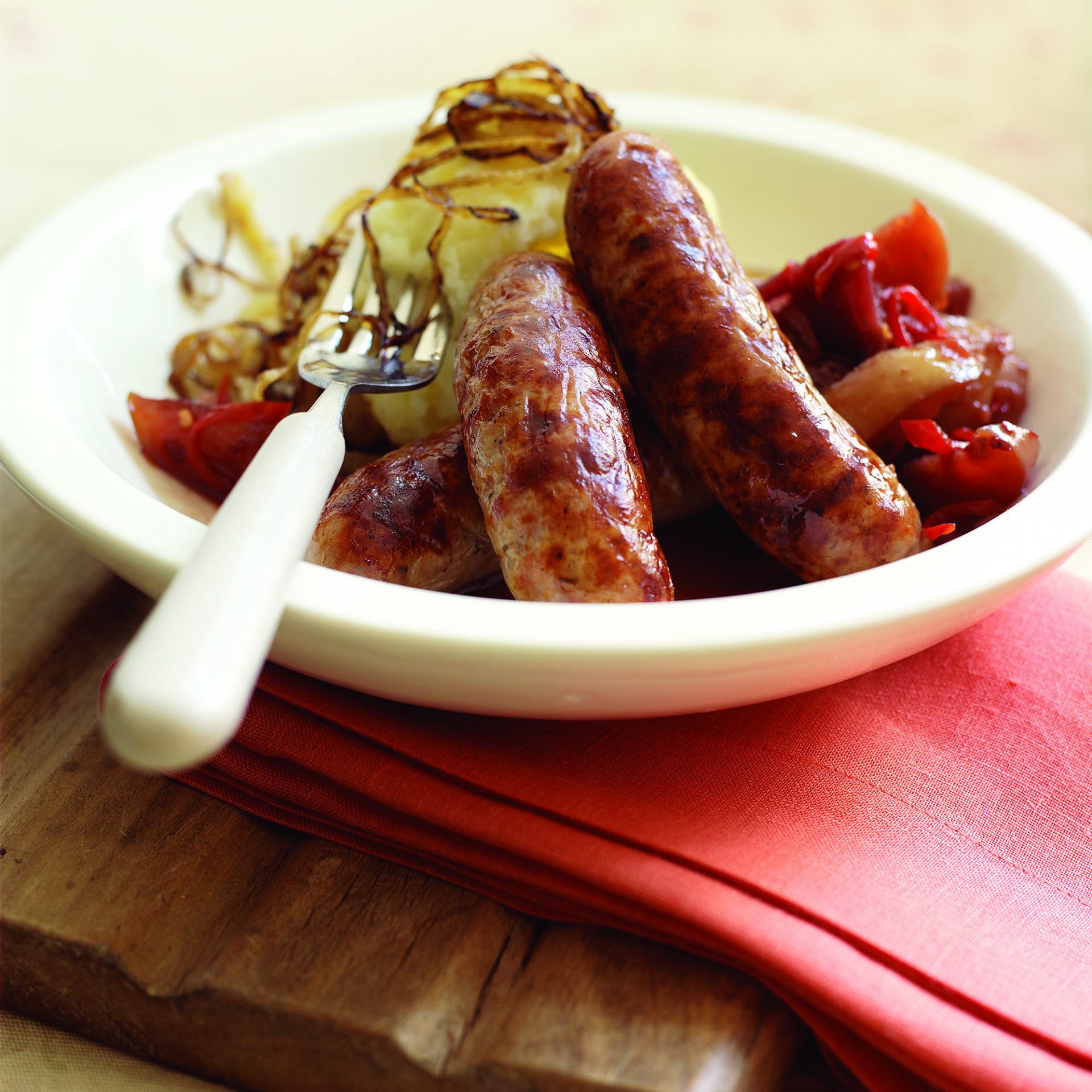 Pork and stilton sausages in a bowl with a fork and napkin