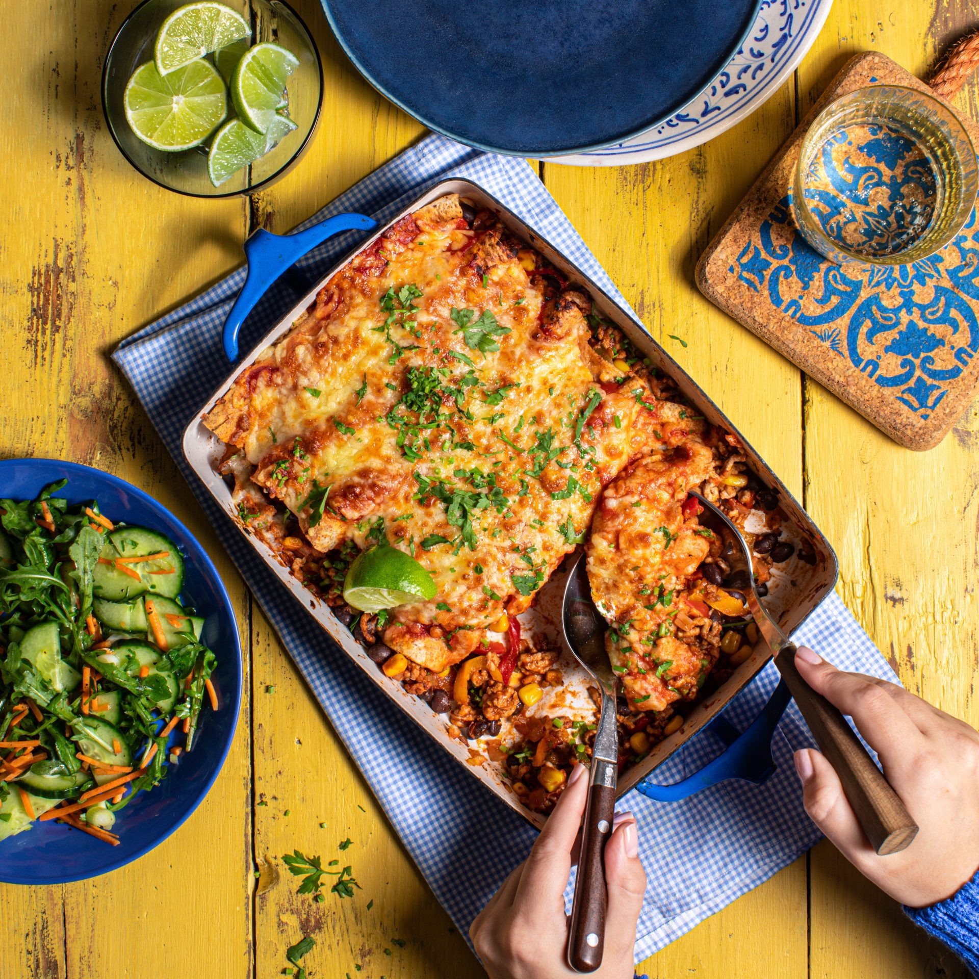 Large baking dish filled with mexican pork enchiladas on a yellow background