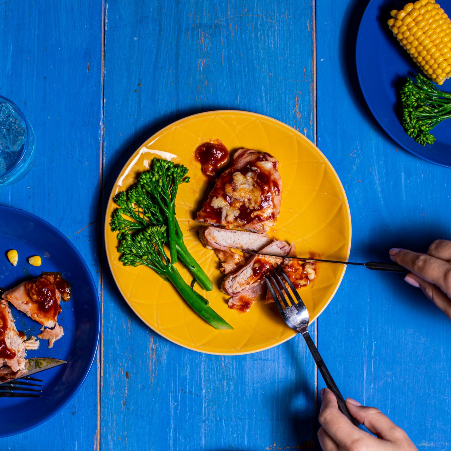 BBQ sauce covered pork steaks served on a yellow plate with broccoli.