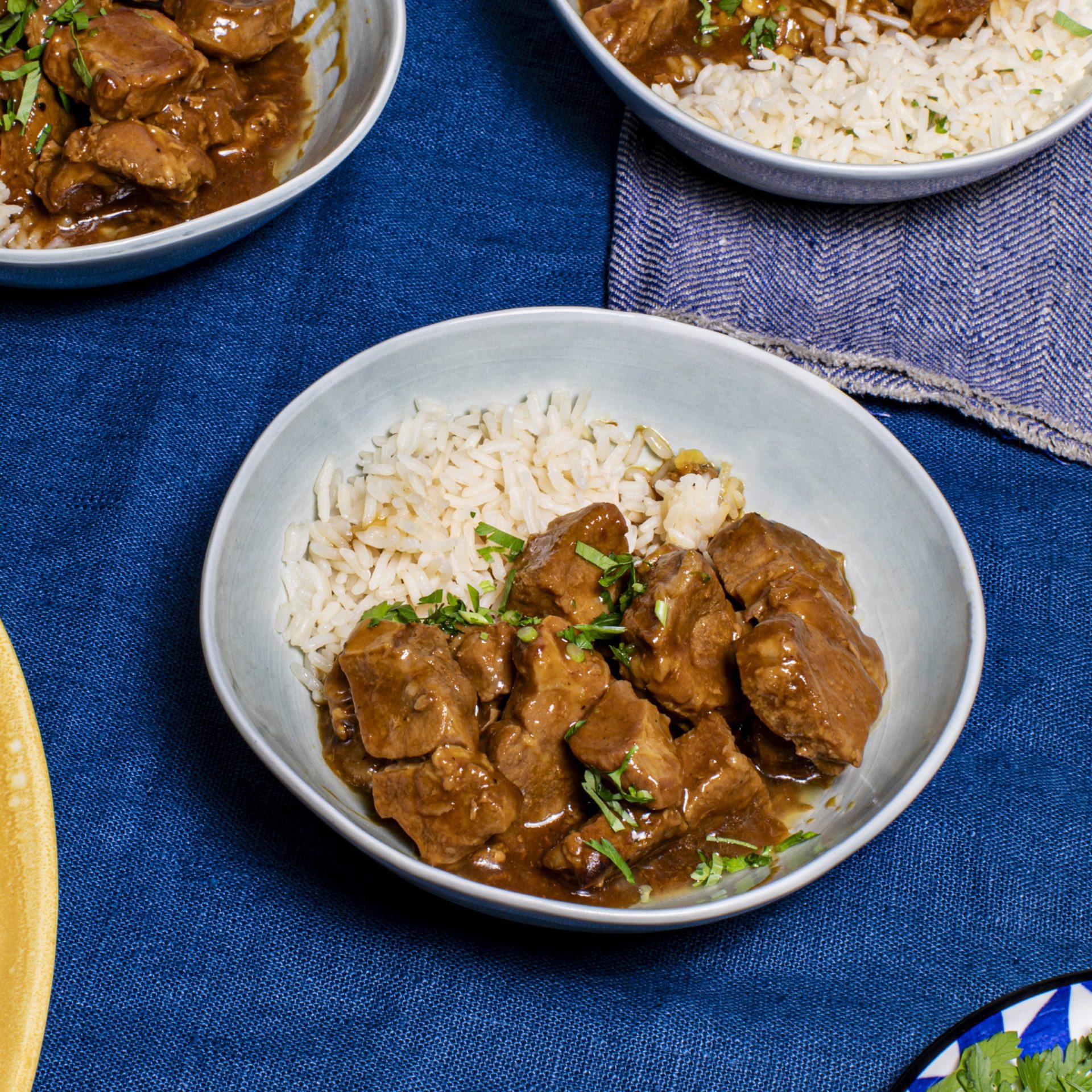 Slow cook hoisin pork with white rice served in a bowl on blue table cloth