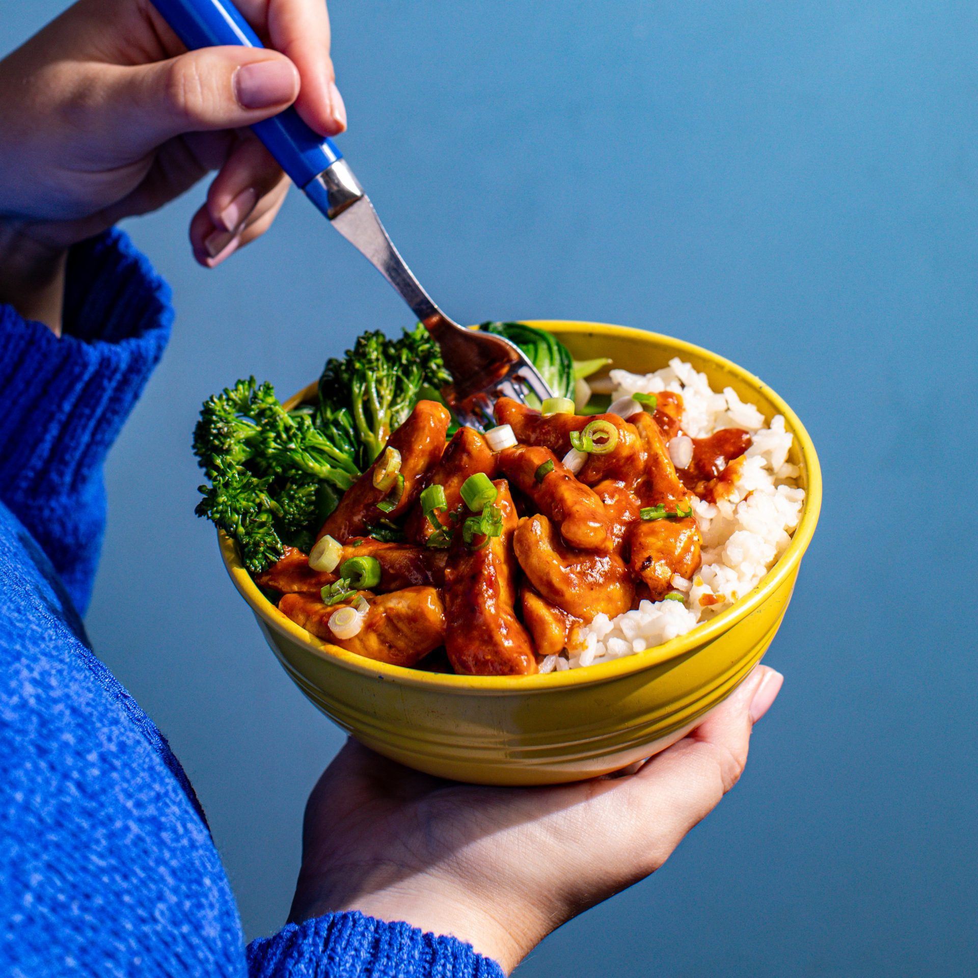 Yellow bowl filled with white rice, broccoli and sweet chilli pork strips.