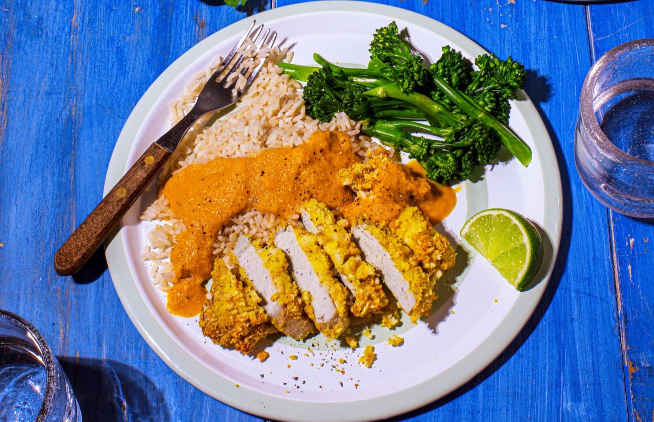 Pork Katsu Style Curry served with white rice and green vegetables on a plate with fork