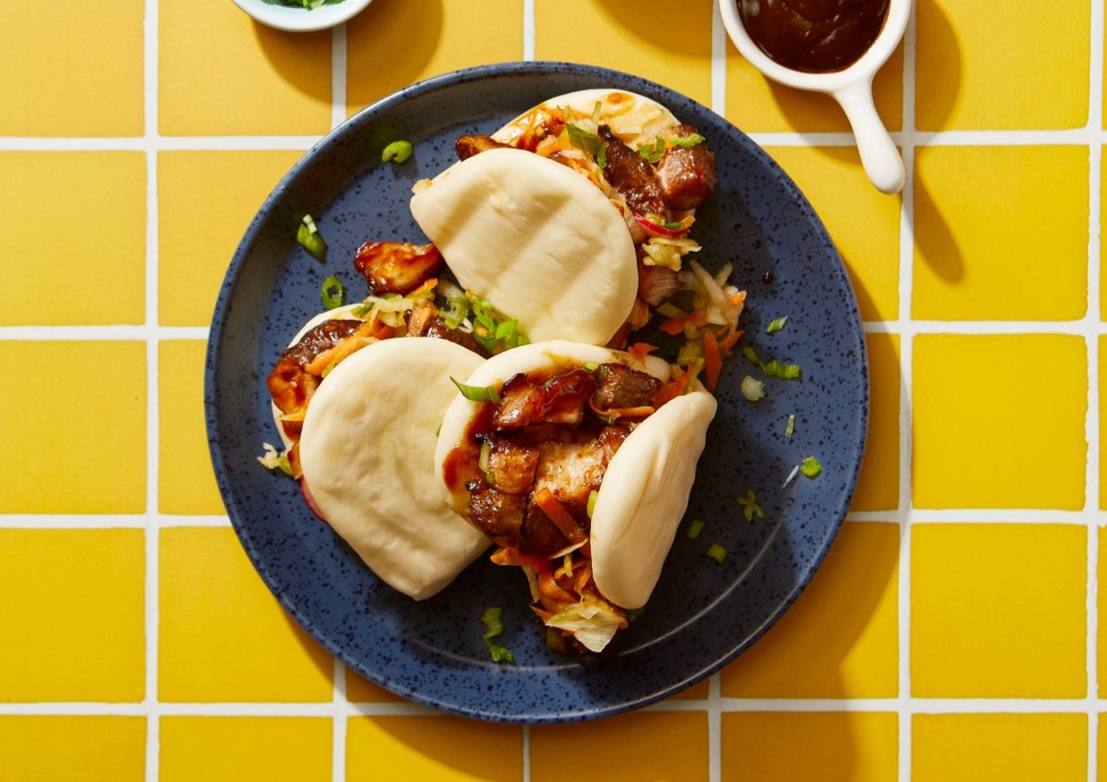 char sui pork belly bao buns on yellow tile background with serving suggestions